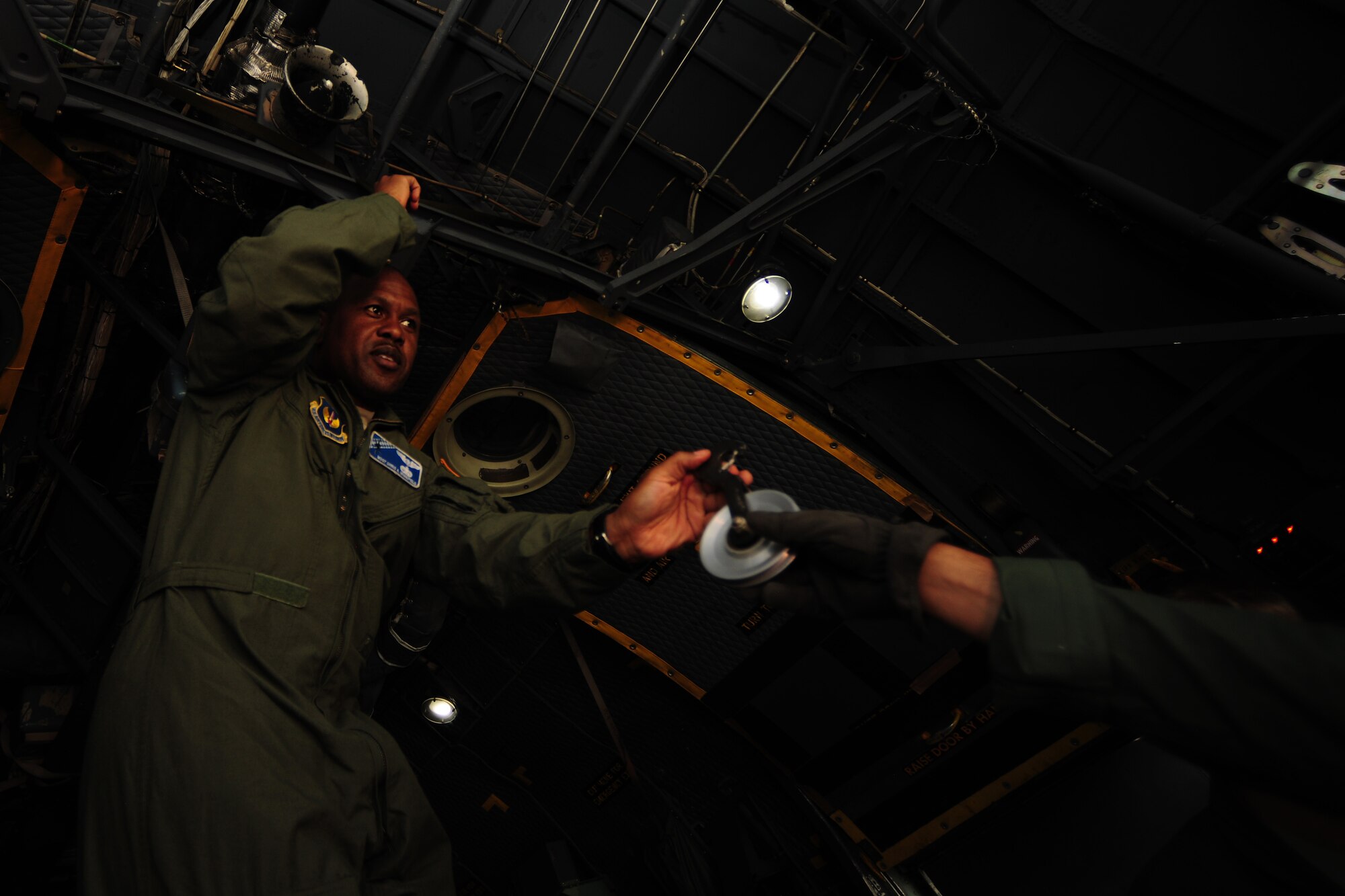 A Polish Air Force C-130E Hercules loadmaster hands U.S. Air Force Master Sgt. Christ Minnifield, 37th Airlift Squadron loadmaster, a tool during a joint mass container delivery airdrop training at Powidz Air Base, Poland, Aug. 11, 2014. During the training, Polish and American forces shared best practices in preparation for Poland to deliver equipment and supplies to Iraq. (U.S. Air Force photo by Staff Sgt. Jarad A. Denton/Released)