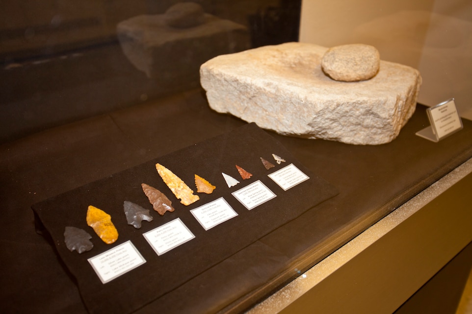 Arrowheads on display at the Combat Center Archaeology and Paleontology Curation Center range from 10,000 years old on the left, to 100 years old on the right. Next to them is a milling slab and hand stone that inhabitants of the installation's Deadman Lake area used to grind things like mesquite beans. (Official Marine Corps photo by Kelly O'Sullivan/Released)