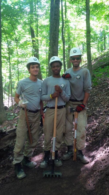 Members of Maple 1 take a break on Chief Illini Trail along Lake Shelbyville in central Illinois. Darius, center, is holding a rake-hoe tool called a Mccleod, while Steven and Vincent are holding pick-axe type tools called a Pulaski.