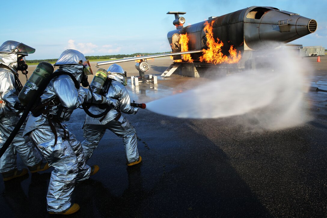 Aircraft Rescue and Firefighting Marines approach a simulated aircraft crash at Marine Corps Air Station Cherry Point, N.C., Aug. 14, 2014. The Marines honed their firefighting skills by dealing with the stressors and procedures of aircraft fires first hand.