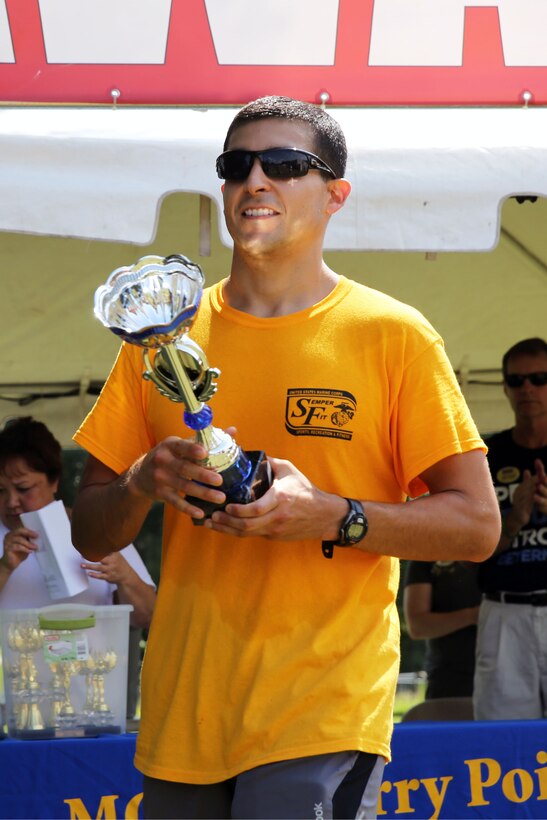 Navy Lt. Andrew Dominguez claims the male first place trophy after finishing the Marine Corps Community Services' Sprint Triathlon/Relay at Marine Corps Air Station Cherry Point, N.C., Aug. 16, 2014. Dominguez is a physical trainer with the Cherry Point's Naval Heath Clinic and native to San Antonio, Texas.