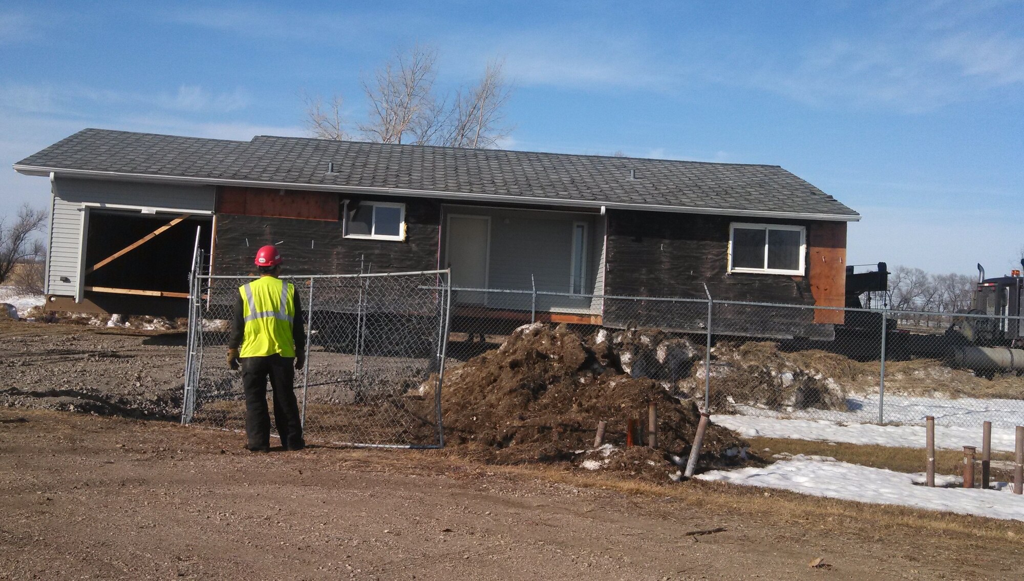 A crew member watches as the first of 31 homes donated this year to Operation Walking Shield is hauled away from Grand Forks Air Force Base, N.D., in the spring of 2014. Operation Walking Shield’s Program Manager, Marvin Thurman, credits the combined efforts of Walking Shield, Balfour Beatty Communities and the Air Force for successfully relocating the homes to the nearby Turtle Mountain Reservation. The homes, which had been marked for demolition, will help fill a stark shortage of housing at the reservation.  (Air Force Photo/Cassandra Spradlin)