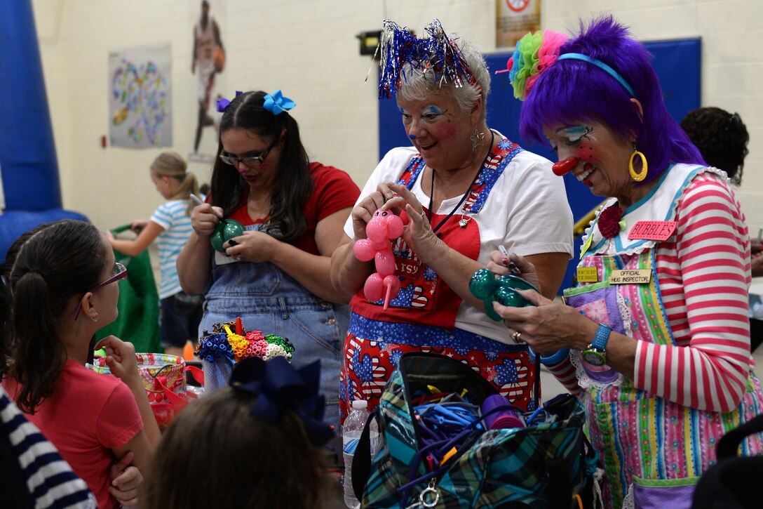 Volunteers dressed as clowns create balloon animals for children during the Back to School Block Party at the Teen and Youth Center at Fort Eustis, Va., Aug. 12, 2014. Families celebrated the end of summer and the beginning of the school year with free food, music and various games and activities. (U.S. Air Force photo by Staff Sgt. Teresa J.C. Aber/Released)