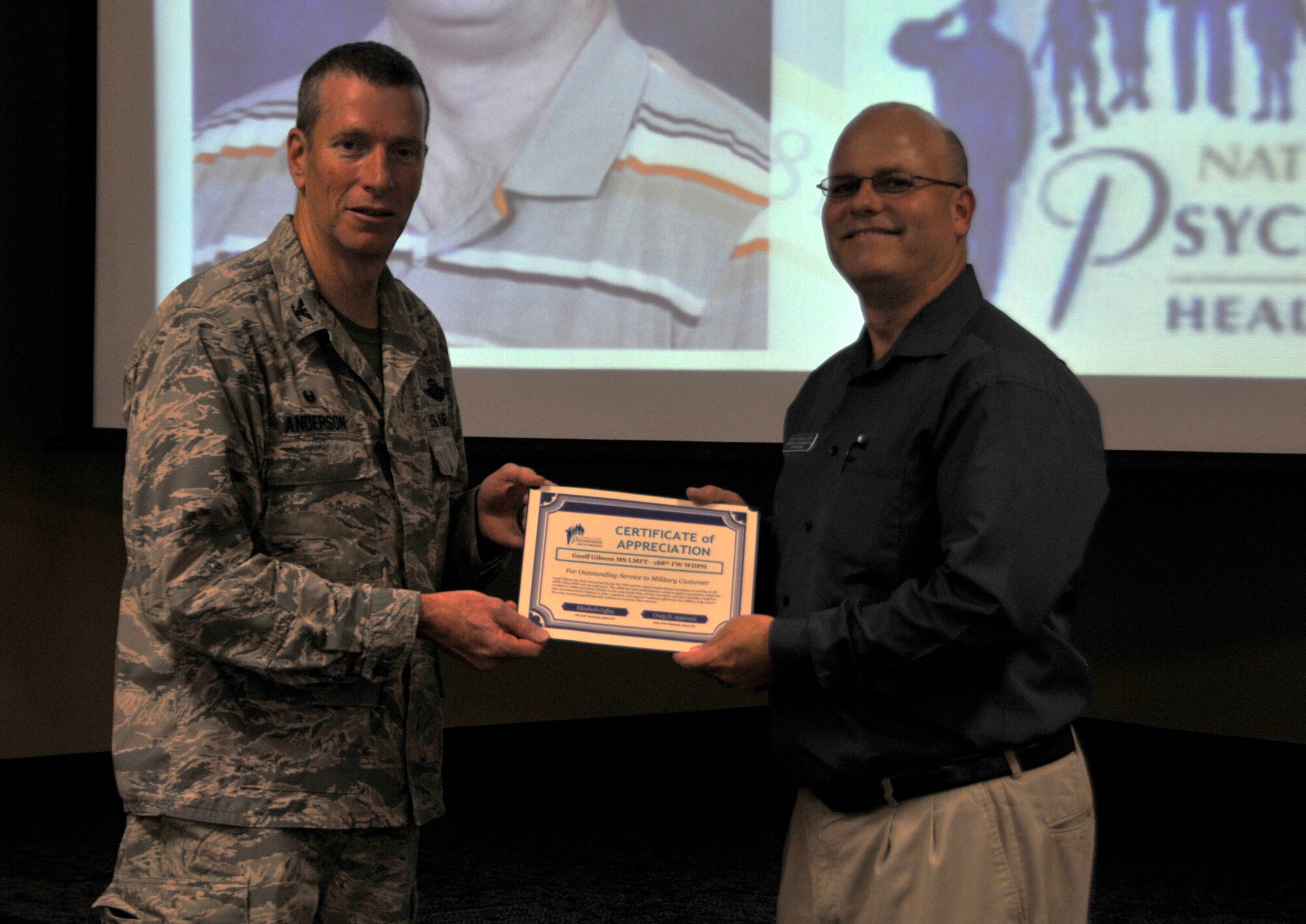 Col. Mark Anderson, 188th Wing commander, left, recognizes Geoff Gibson as the first-ever Air National Guard Director of Psychological Health of the Year. Gibson’s achievement was recognized at a wing commander’s call held at Ebbing Air National Guard Base, Aug. 3, 2014. This award recognizes an outstanding DPH who shows true dedication to service members and their families. (U.S. Air National Guard photo by Staff Sgt. John Suleski/released)
