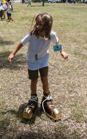 A Joint Base Pearl Harbor-Hickam youth attempts to walk in deep sea boots during Operation Hele On on JBPHH, Hawaii, Aug. 15, 2014. Hele On is a mock deployment line intended to help children understand the process parents go through before a deployment. (U.S. Air Force photo by Tech. Sgt. Terri Paden)