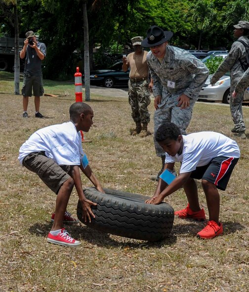 Two Joint Base Pearl Harbor-Hickam youths flip a tire toward the finish line as part of a relay race during Operation Hele On Aug. 15, 2014. Hele On is a mock deployment line intended to help children understand the process parents go through before a deployment. More than 130 children attended the full day event which included an intelligence briefing, mobility bag pickup, obstacle course, drill competition, combat arms training and a C-17 static tour. (U.S. Air Force photo by Tech. Sgt. Terri Paden)