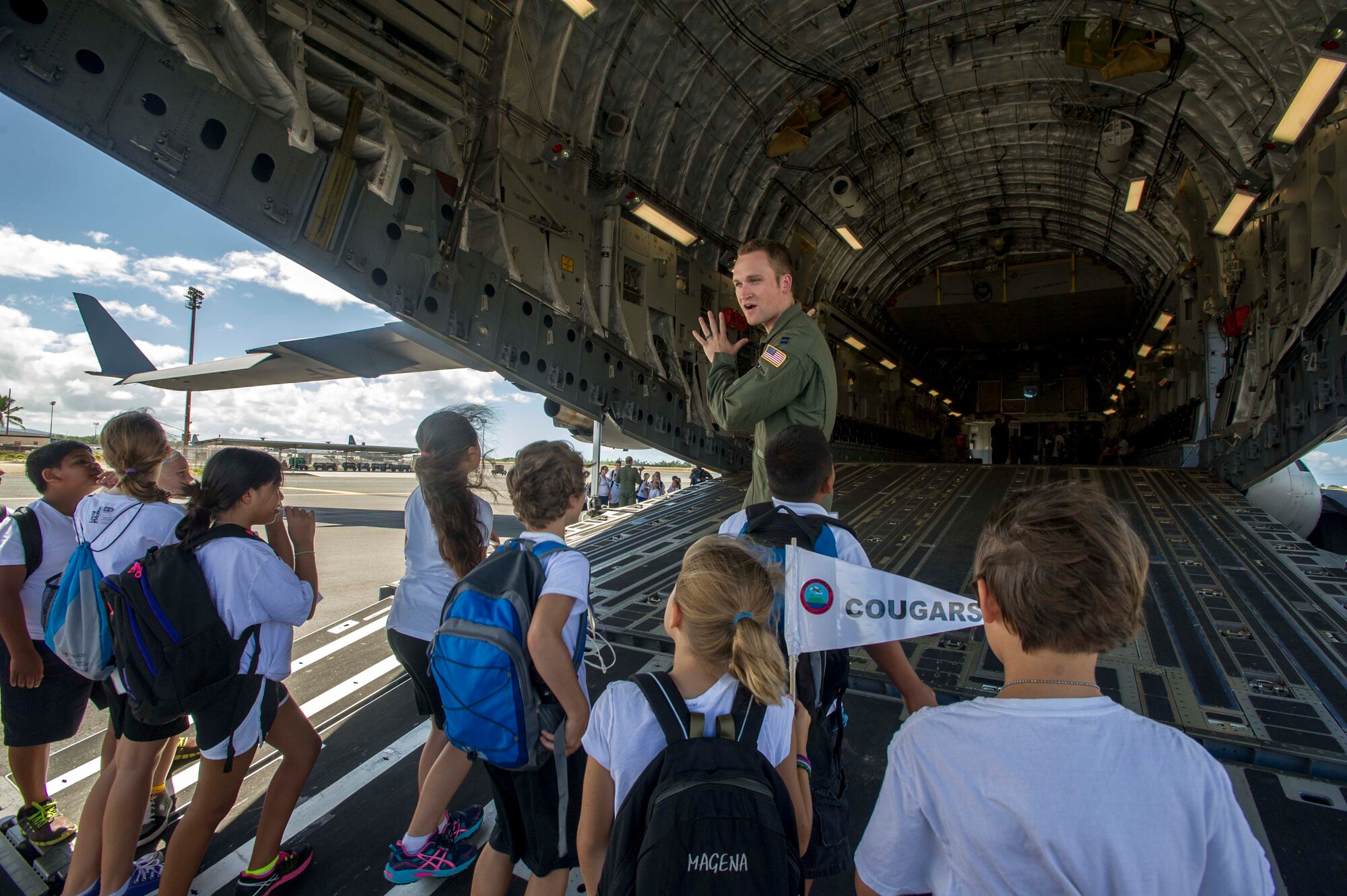 Capt. James Hammelman, 535th Airlift Squadron pilot, conducts a tour of a C-17 Globemaster III on the flightline at Joint Base Pearl Harbor-Hickam, Hawaii, Aug. 15, 2014, during Operation Hele On, a mock deployment line intended to help children understand the process parents go through before a deployment. More than 130 children attended the full day event which included an intelligence briefing, mobility bag pickup, obstacle course, drill competition, combat arms training and a C-17 static tour. (U.S. Air Force photo by Tech. Sgt. Terri Paden)
