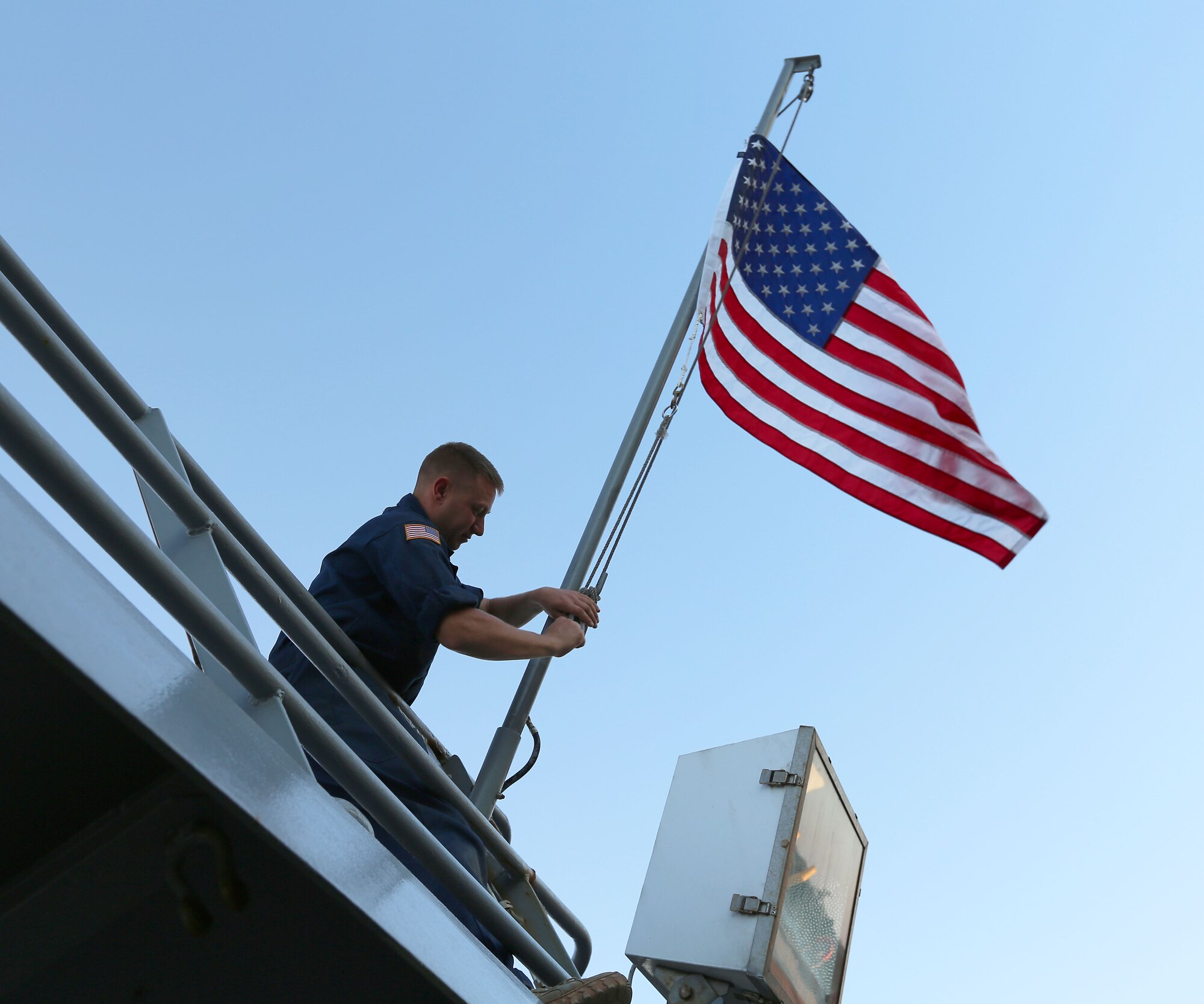 U.S. Army Spc. Ryan Sullivan, 7th Transportation Brigade (Expeditionary) watercraft operator, raises the ensign onto the mast of the U.S. Army Vessel Hobkirk during a Joint Logistics Over-the-Shore exercise with Joint Task Force Civil Support at Fort Eustis, Va., Aug. 14, 2014. The exercise involved loading and unloading ships without the benefit of a fixed port facility. (Department of Defense photo by U.S. Navy Petty Officer 1st Class Brian Dietrick/Released)