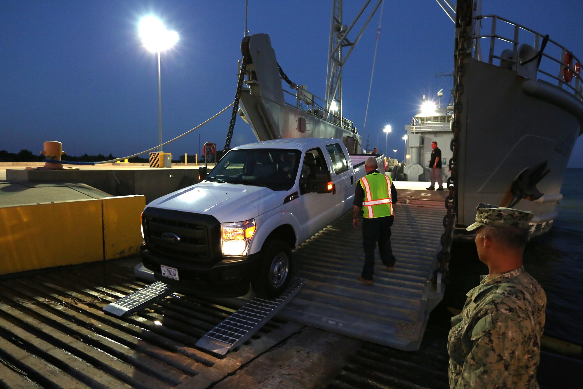 U.S. Army Sgt. Nathan Love, 7th Transportation Brigade (Expeditionary) boatswain, guides a Joint Task Force Civil Support vehicle onto U.S. Army Vessel Hobkirk during a Joint Logistics Over-the-Shore exercise at Fort Eustis, Va., Aug. 14, 2014. JLOTS is the process of loading and unloading equipment and vehicles on vessels without the benefit of a fixed port facility. (Department of Defense photo by U.S. Navy Petty Officer 1st Class Brian Dietrick/Released)