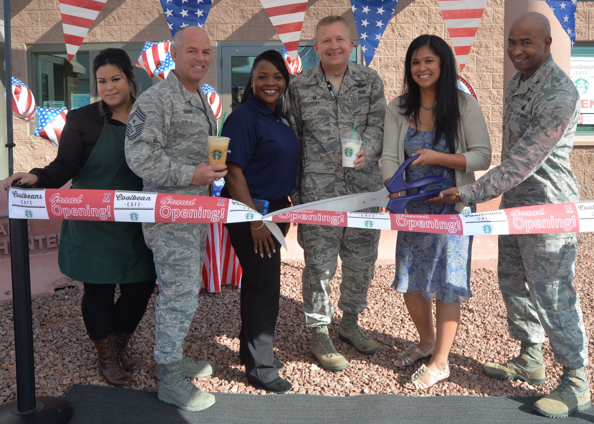 From left to right, Chief Master Sgt. Butch Brien, 432nd Wing/432nd Air Expeditionary Wing command chief, Col. James Cluff, 432nd Wing commander and Col. Richard Neal, 799th Air Base Group commander welcome Coolbeans Café owner, Roselle Gereda and her staff to Creech Air Force Base, Nev., during a ribbon cutting ceremony, Aug. 12, 2014. The new coffee shop is located in Building 1003 and is open from 7 a.m. to 4 p.m. Monday through Friday to provide Airmen coffee, snacks and a relaxing atmosphere. (U.S. Air Force photo by Tech. Sgt. Nadine Barclay/Released)