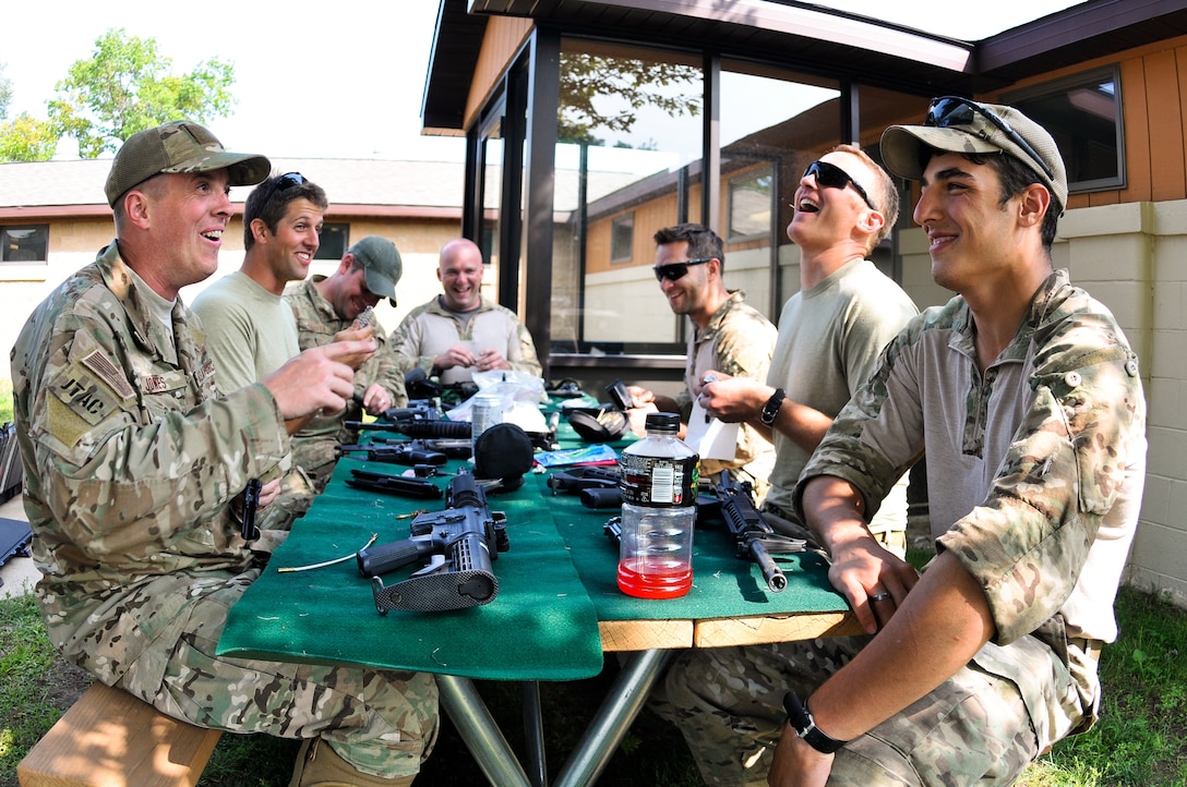 Tactical air control party specialists with the 169th Air Support Operations Squadron share a moment of comradery at the table while cleaning their M4 carbines