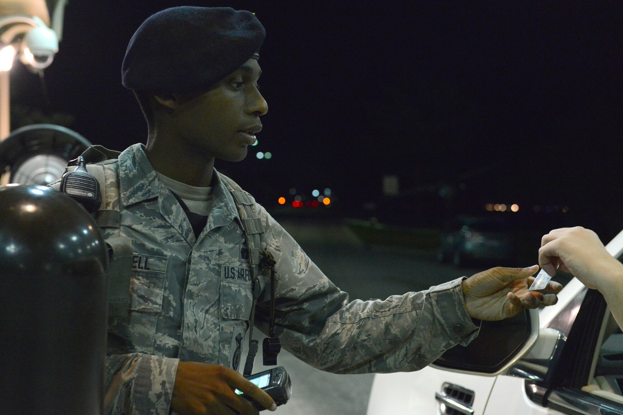 U.S. Air Force Airman 1st Class Dewayne Mitchell, 20th Security Forces Squadron entry controller, checks an identification card at the main gate at Shaw Air Force Base, S.C., Aug. 19, 2014. Mitchell has been a member of the 20th SFS for nine months and ensures only authorized personnel enter the base, no matter the time of day or night. (U.S. Air Force photo by Airman 1st Class Diana M. Cossaboom/Released)