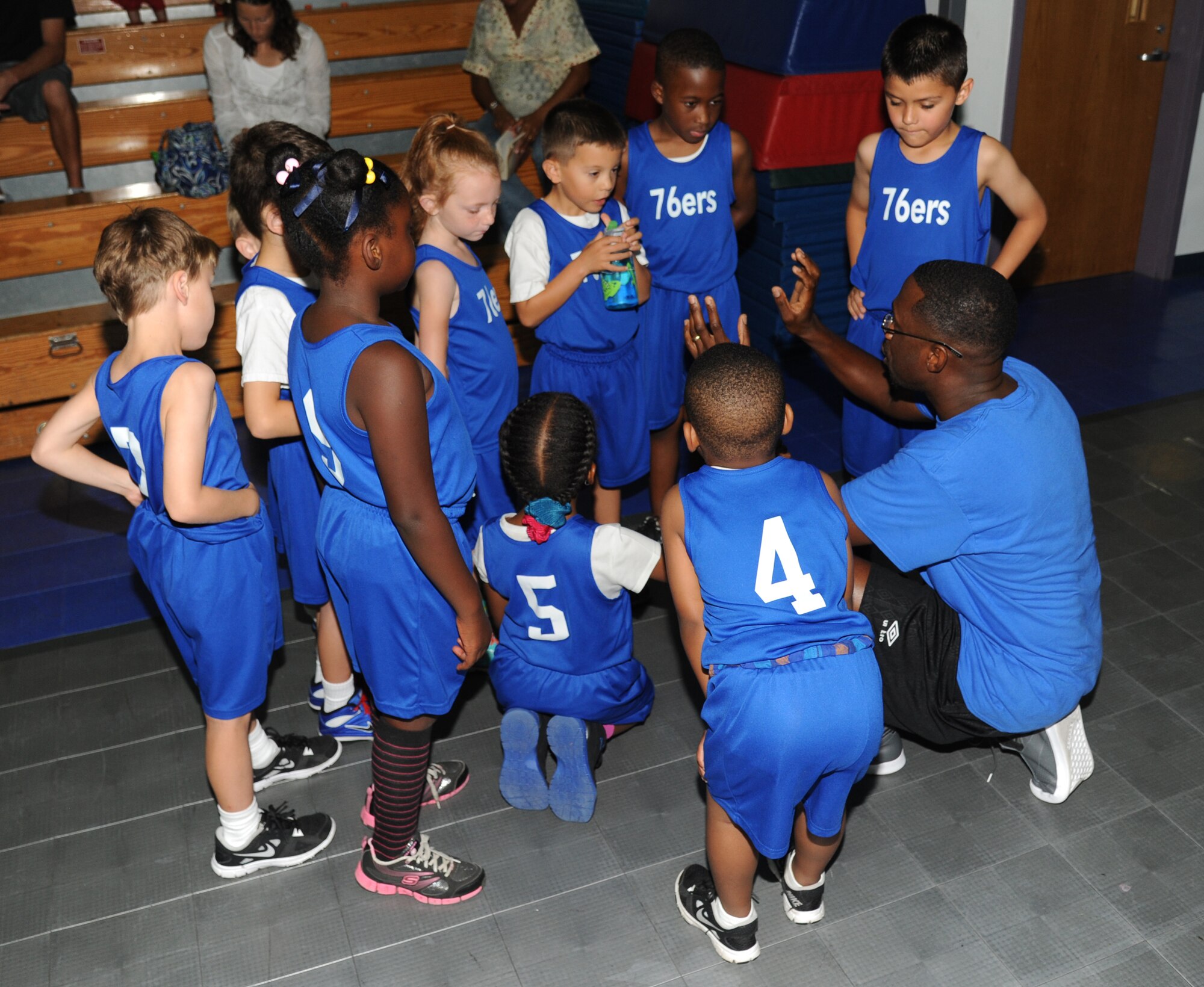 Staff Sgt. Scott Johnson, 345th Airlift Squadron and the “76ers” coach, speaks to his team between quarters during a youth basketball game Aug. 16, 2014, at the Youth Center, Keesler Air Force Base, Miss.  This was a friendly game between the 76ers and the Knicks five-to-seven year old teams. (U.S. Air Force photo by Kemberly Groue)