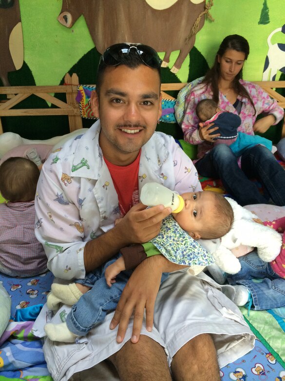 Senior Airman Andy Lopez, 437th Aircraft Maintenance Squadron crew chief, feeds a small child from La Casa de la Madre y El Nino while on his off time during a U.S. Southern Command Capstone mission. The aircrew donated supplies and toys to the orphanage and spent hours playing with and caring for the children. (Courtesy photo by Maj. Adam Dalson)