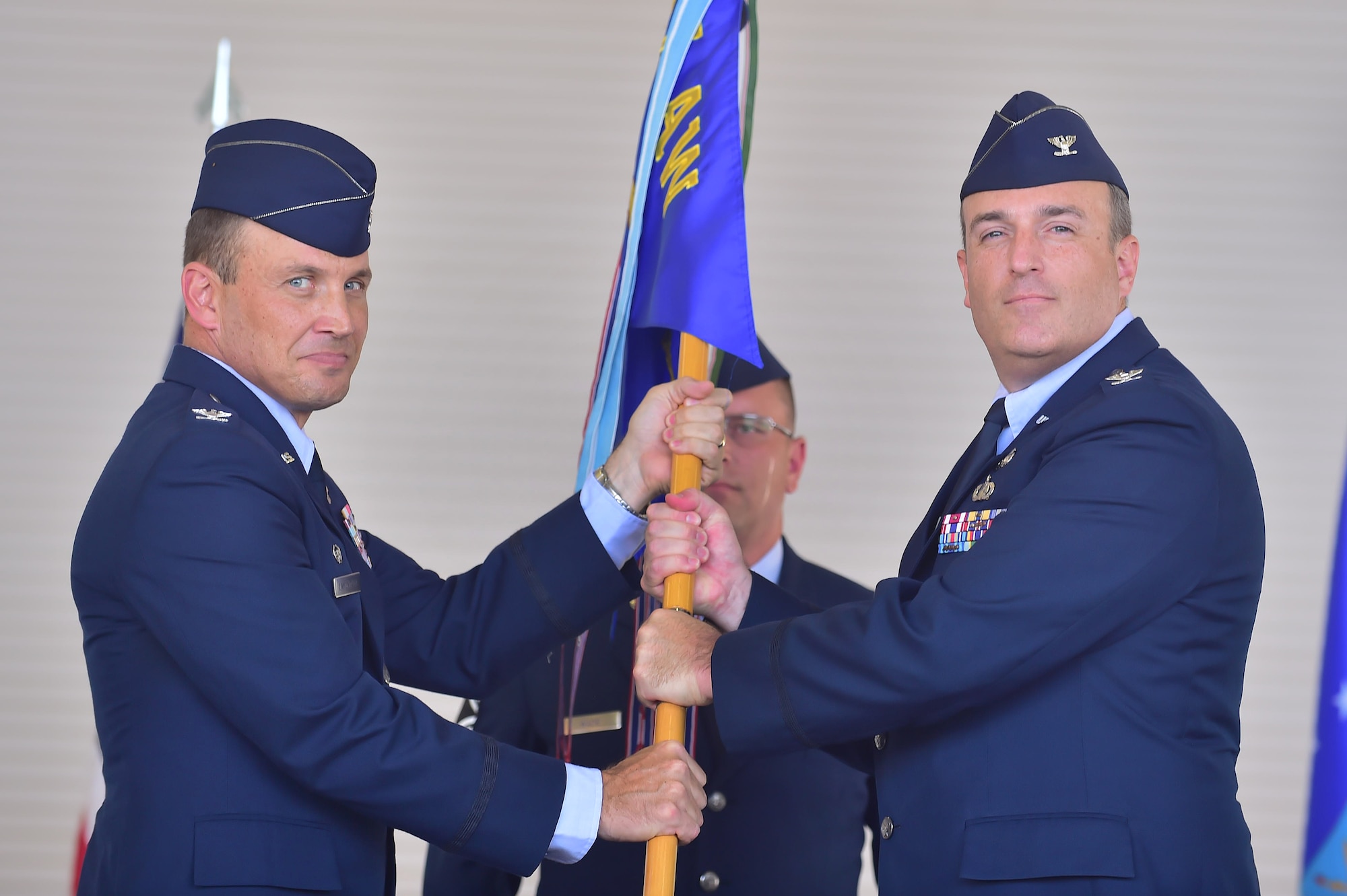 Colonel John Lamontagne, 437th Airlift Wing commander, passes the 437th Maintenance Group guidon to Col. Brian Peters, 437th Maintenance Group commander during the 437th MXG Change of Command Aug. 15, 2014, at Joint Base Charleston, S.C. Col. Colonel Dennis Dabney relinquished command of the group to Peters, whose previous position was as 436th Maintenance Operations Group deputy commander, Dover Air Force Base, Del. (U.S. Air Force photo/Senior Airman George Goslin)