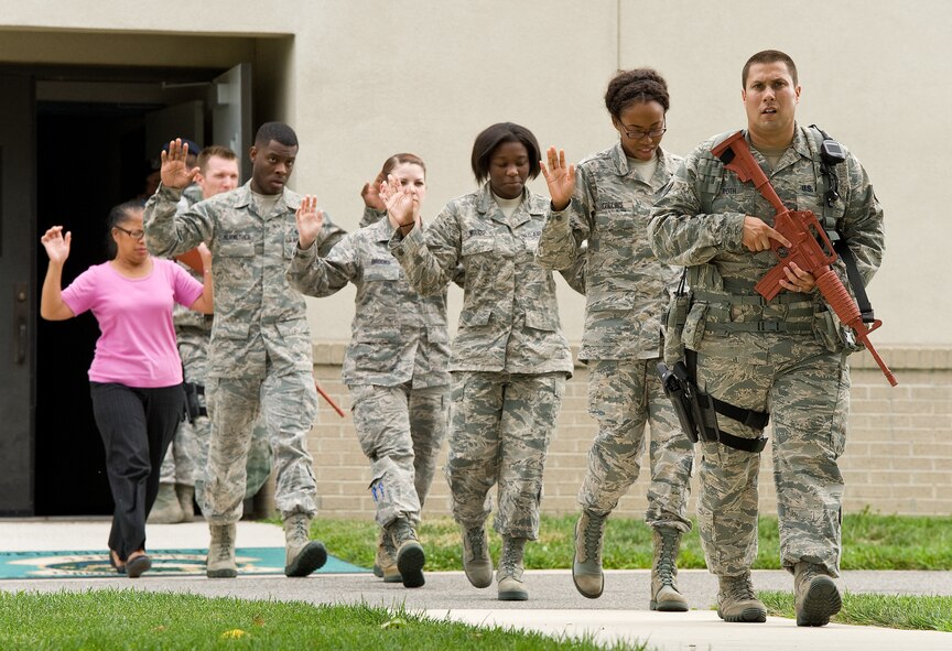 Staff Sgt. Michael Roth, right, 436th Security Forces Squadron, leads five simulated hostages out of a building during an active shooter exercise Aug. 1, 2014, at Dover Air Force Base, Del. Roth and other SFS members neutralized an active shooter, performed a building sweep and rescued hostages as part of a major accident response exercise. (U.S. Air Force photo/Roland Balik)