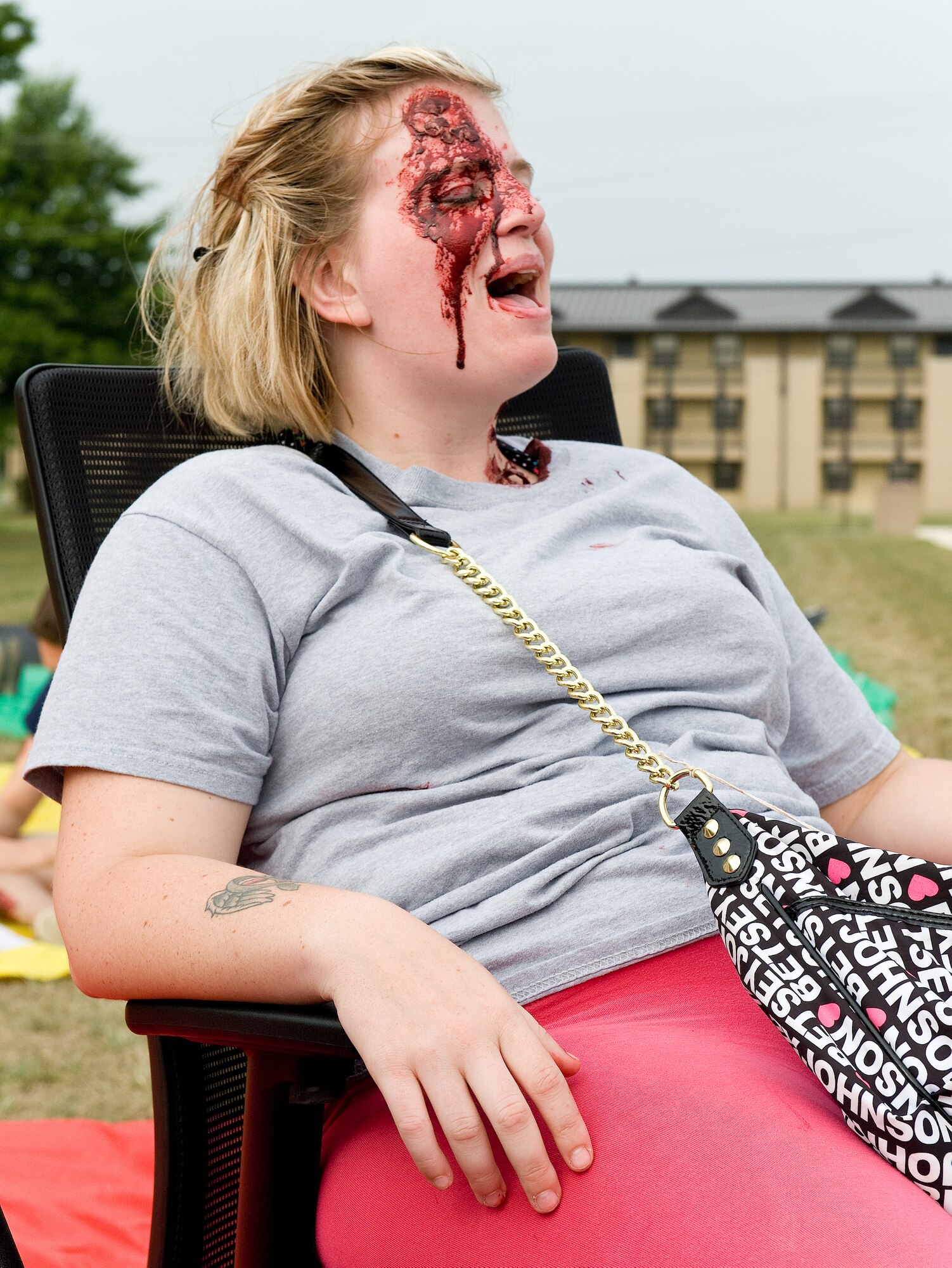 Airman 1st Class Kylie Sisson, 436th Medical Operations Squadron pediatric medical technician, cries for medical attention during an active shooter exercise Aug. 1, 2014, at Dover Air Force Base, Del. Sisson played the role of a victim and had moulage applied to her head and neck to simulate gunshot wounds she received. (U.S. Air Force photo/Roland Balik)