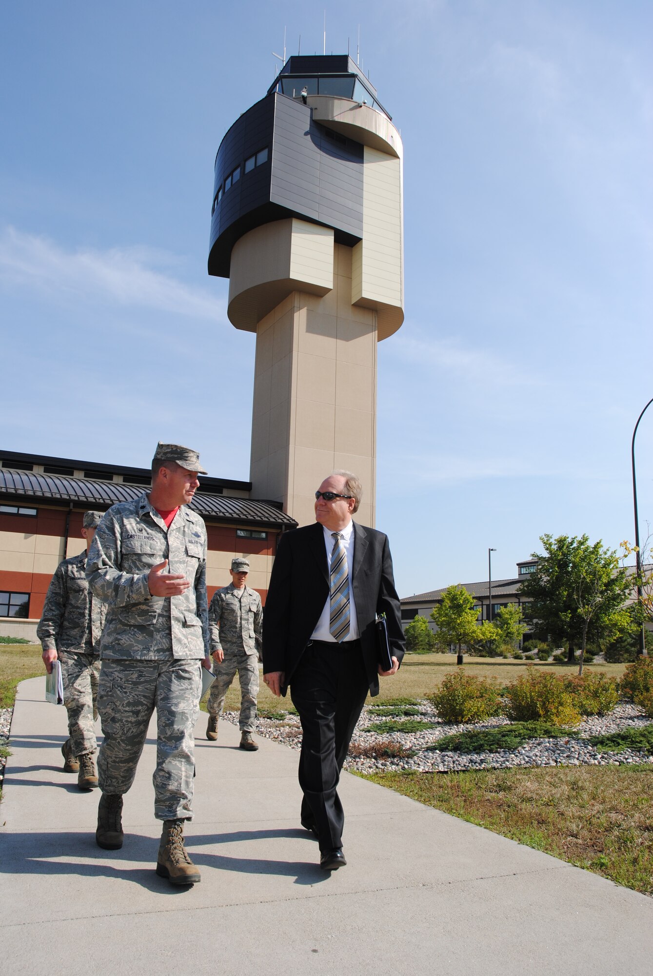 Jim Williams, Federal Aviation Administration Unmanned Aircraft Systems Integration Office manager, talks with Lt. Col. Jonathan Castellanos, 319th Operations Support Squadron commander about UAS integration goals as they leave the air traffic control tower on Grand Forks Air Force Base, N.D., on Aug. 15, 2014. Williams visited the Radar Approach Control Tower, as one of the stops on tour incorporated into his official visit to the base. The RAPCON tower is the primary facility used by the Air Force for directing approaches and departures of all aircraft in and out of the installation, to include Unmanned Aerial Vehicles. (U.S. Air Force photo/Staff Sgt. Luis Loza Gutierrez)