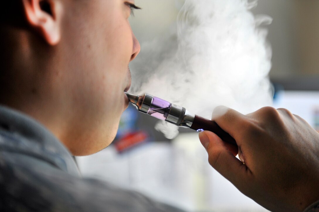 A Scott Airman uses an e-cigarette, Scott Air Force Base, Ill., Aug. 13, 2014. The use of e-cigarettes has become more popular, for a variety of reasons. The tank, or container of the e-cigarette holds liquid flavoring and typically nicotine, and a vaporizer which evaporates the liquid, or juice, as it is sometimes called, that is inhaled by the user. States’ attorneys general around the U.S. have pressured the FDA to apply regulations to the e-cigarette industry. (U.S. Air Force photo by Airman 1st Class Erica Crossen)