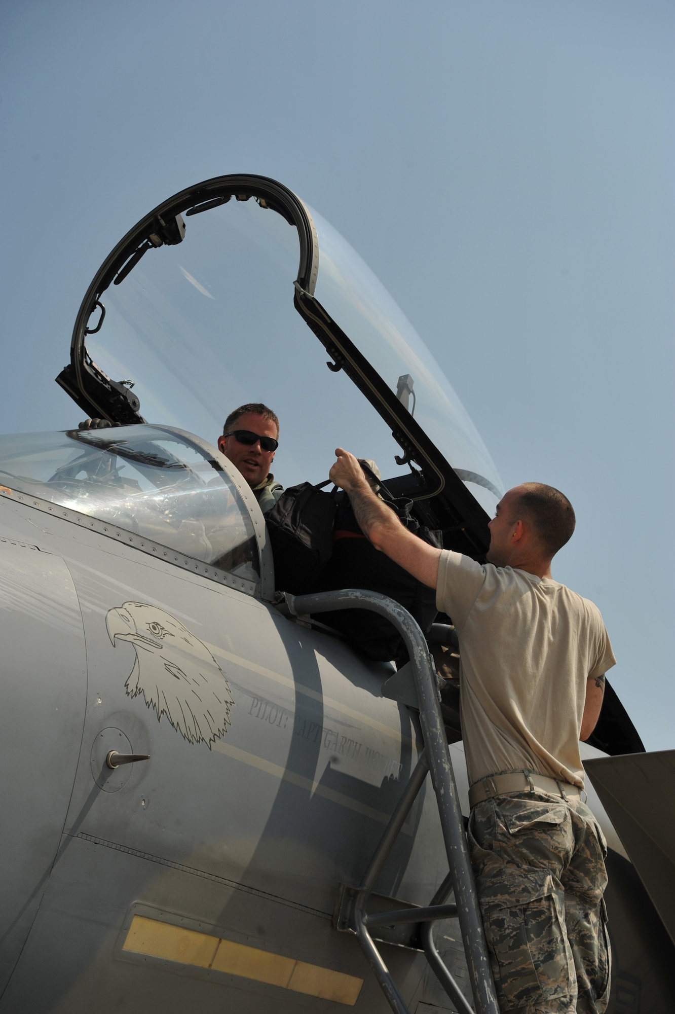 Senior Airman Jeffrey Berry (right), 493rd Fighter Squadron aircrew flight equipment technician, receives a harness and vest from a pilot after his flight Aug. 15, 2014. Aircrew flight equipment Airmen provide pilots with the life-saving equipment which allows them to fly. (U.S. Air Force photo/Senior Airman Hailey Haux)