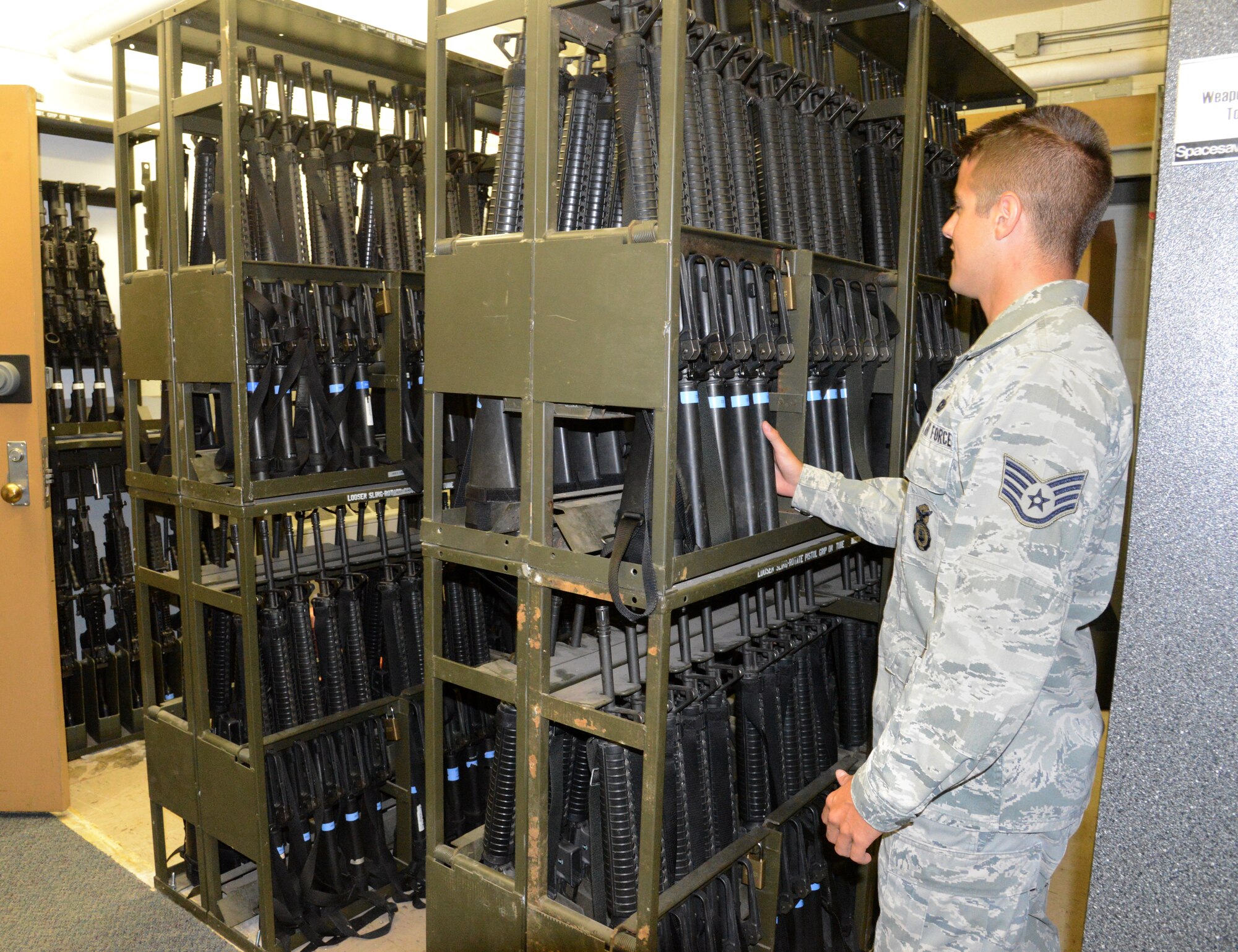 Staff Sgt. Michael Enerud retrieves a weapon from a new section of inventory in the Security Forces armory. He, along with the other SFS members who work there, took the initiative to reorganize the area to make it more efficient for SFS members needing to check in/out weapons and ammunition for their shifts. The ‘Just Do It’ initiative will save the government more than $373,000 a year. 
(Air Force photo by Kelly White)
