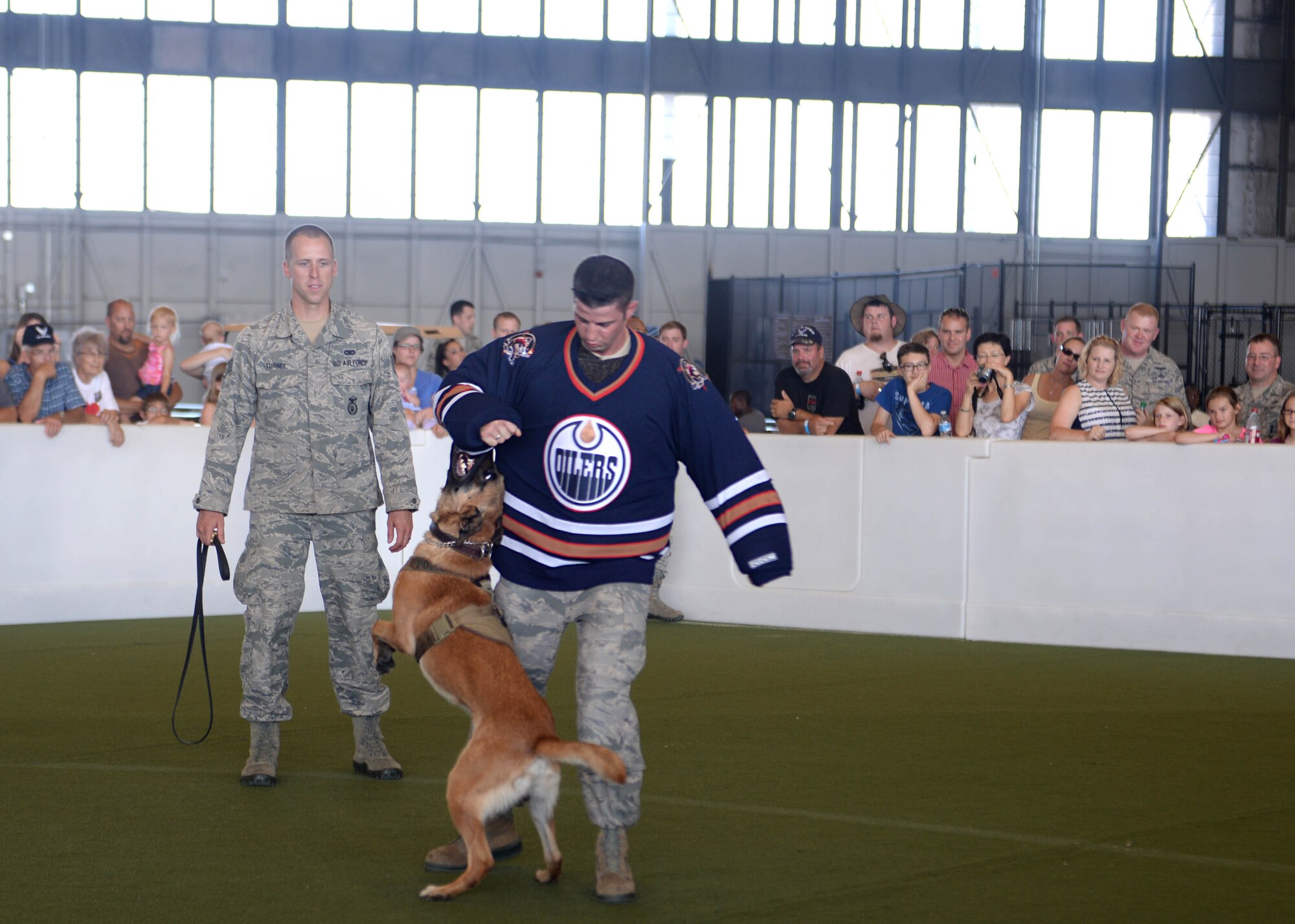 Staff Sgt. Brian Turney (left), 28th Security Forces Military Working Dog handler, performs a MWD demonstration with his dog, Nnicholas, and Staff Sgt. John Whisman, 28th SFS MWD trainer, during Ellsworth’s Black Hills Community Appreciation Day, Aug. 16, 2014. During the demo, Carpenter showed spectators various capabilities the dogs posses, all aimed at accomplishing the unique mission of the MWD teams. (U.S. Air Force Photo by Airman 1st Class Rebecca Imwalle/ Released)