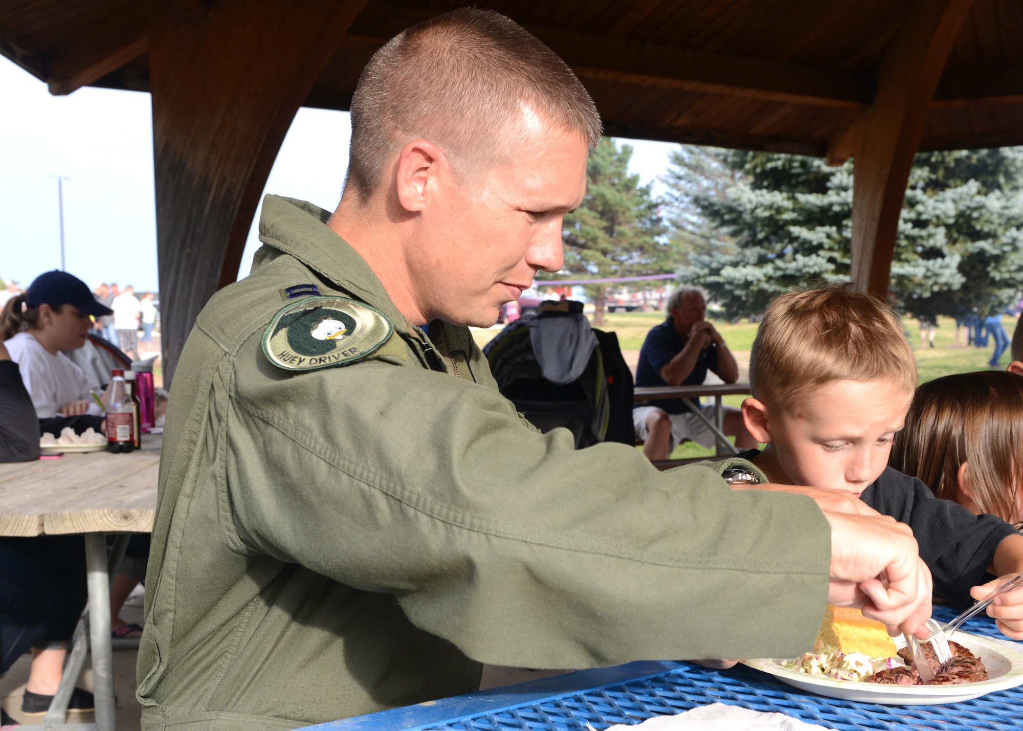 Capt. Barry Gordon, 40th Helicopter Squadron UH-1N Huey helicopter pilot, cuts steak for his son, David, during a free steak dinner Aug. 15 at Sun Plaza Park at Malmstrom Air Force Base, Mont. Of the 1,200 steaks provided for Team Malmstrom, 250 of those went to Airmen on duty posted to Malmstrom’s missile complex and were unable to attend the dinner. (U.S. Air Force photo/Senior Airman Katrina Heikkinen)