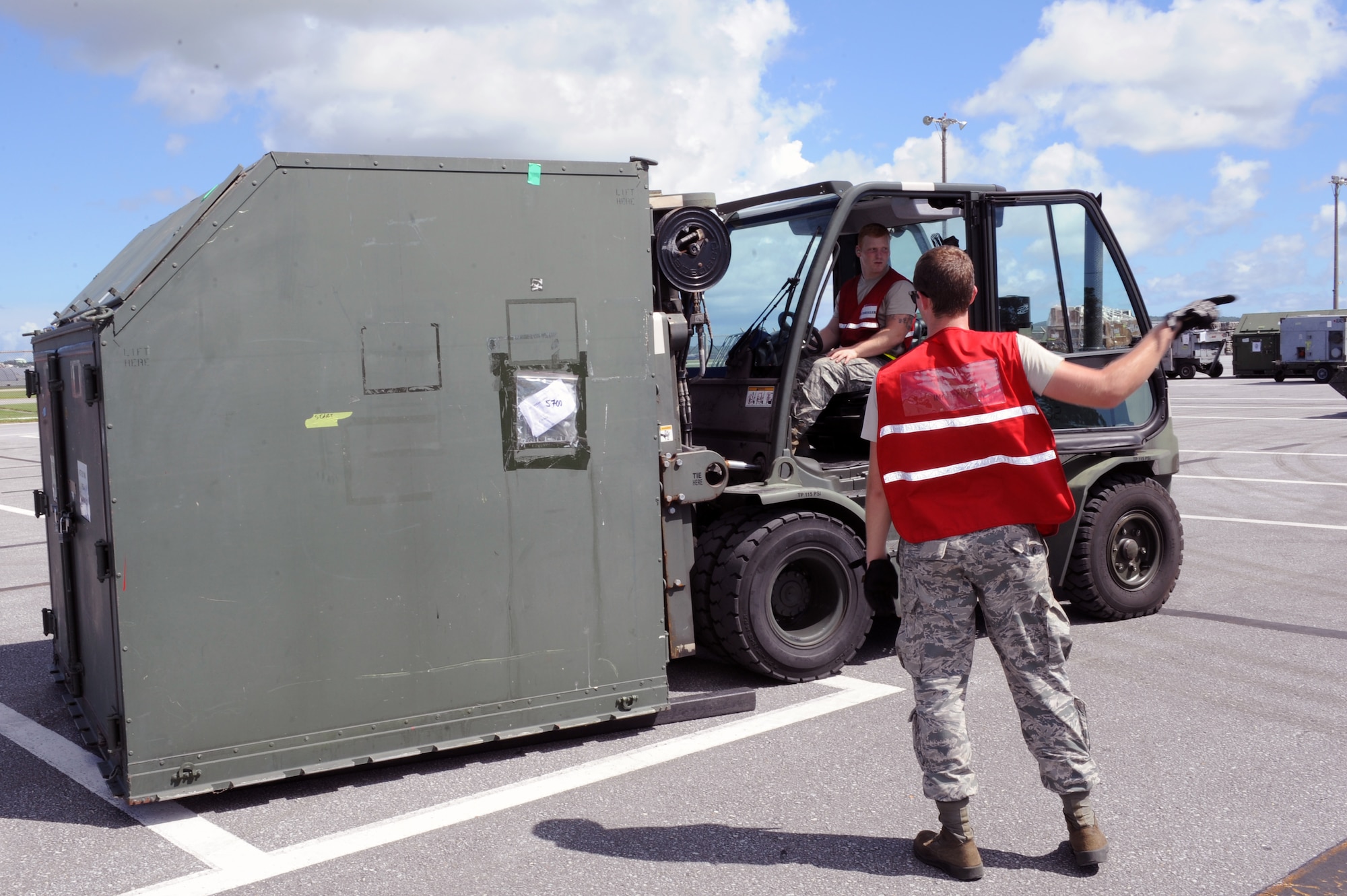U.S. Air Force Airman 1st Class Brandon Craver, 18th Logistics Readiness Squadron fuels operator, marshalls Airman 1st Class Reinhardt Andersen, 18th LRS fuels distribution operator, as he transports cargo to be weighed on Kadena Air Base, Japan, Aug. 19, 2014. Airmen from the 18th LRS participated in a mission focused exercise by checking the weight and dimensions of shipping containers against a cargo manifest to practice the proper deployment of aircraft parts and maintenance equipment. (U.S. Air Force photo by Airman 1st Class Zade C. Vadnais/Released) 
