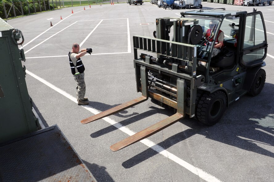 U.S. Air Force Senior Airman Jerry Duvall, 18th Logistics Readiness Squadron air terminal operations journeyman, marshalls Staff Sgt. Mykel Wilson, 18th LRS fuels distribution supervisor, as he lowers a forklift’s forks on Kadena Air Base, Japan, Aug. 18, 2014. After checking the weight and dimensions of shipping containers against a cargo manifest, Airmen from the 18th LRS loaded the cargo onto trucks to simulate delivery in support of a mission focused exercise. (U.S. Air Force photo by Airman 1st Class Zade C. Vadnais) 
