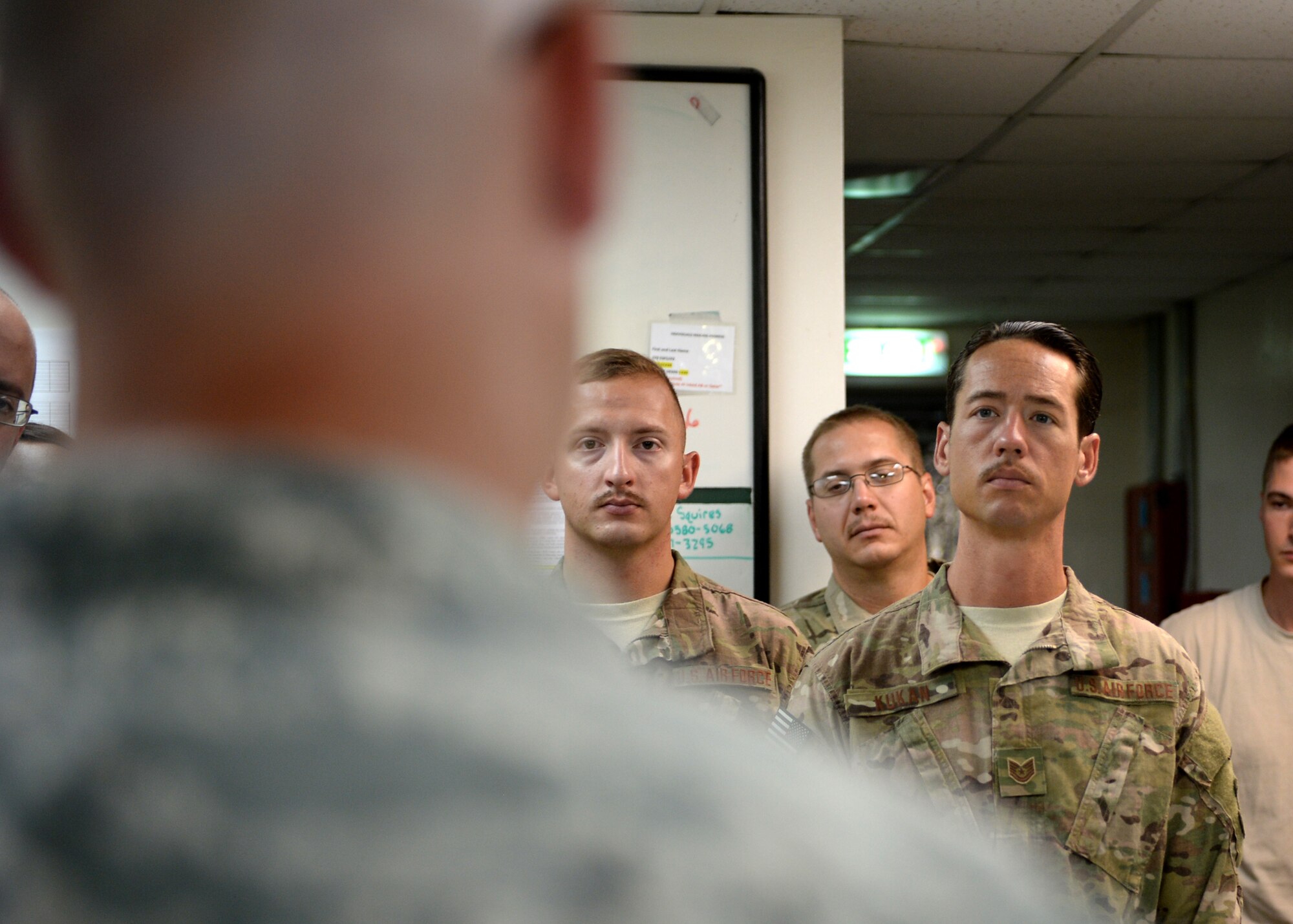 Tech. Sgt. John Kukan, U.S. Air Forces Central Band Starlifter guitarist, listens to a briefing about military working dogs at the 379th Expeditionary Security Forces Squadron kennel, Aug. 18, 2014, Al Udeid Air Base, Qatar. The MWD flight gave a show of force demonstration to the band prior to their last performance while deployed. (U.S. Air Force photo by Staff Sgt. Shawn Nickel/Released)