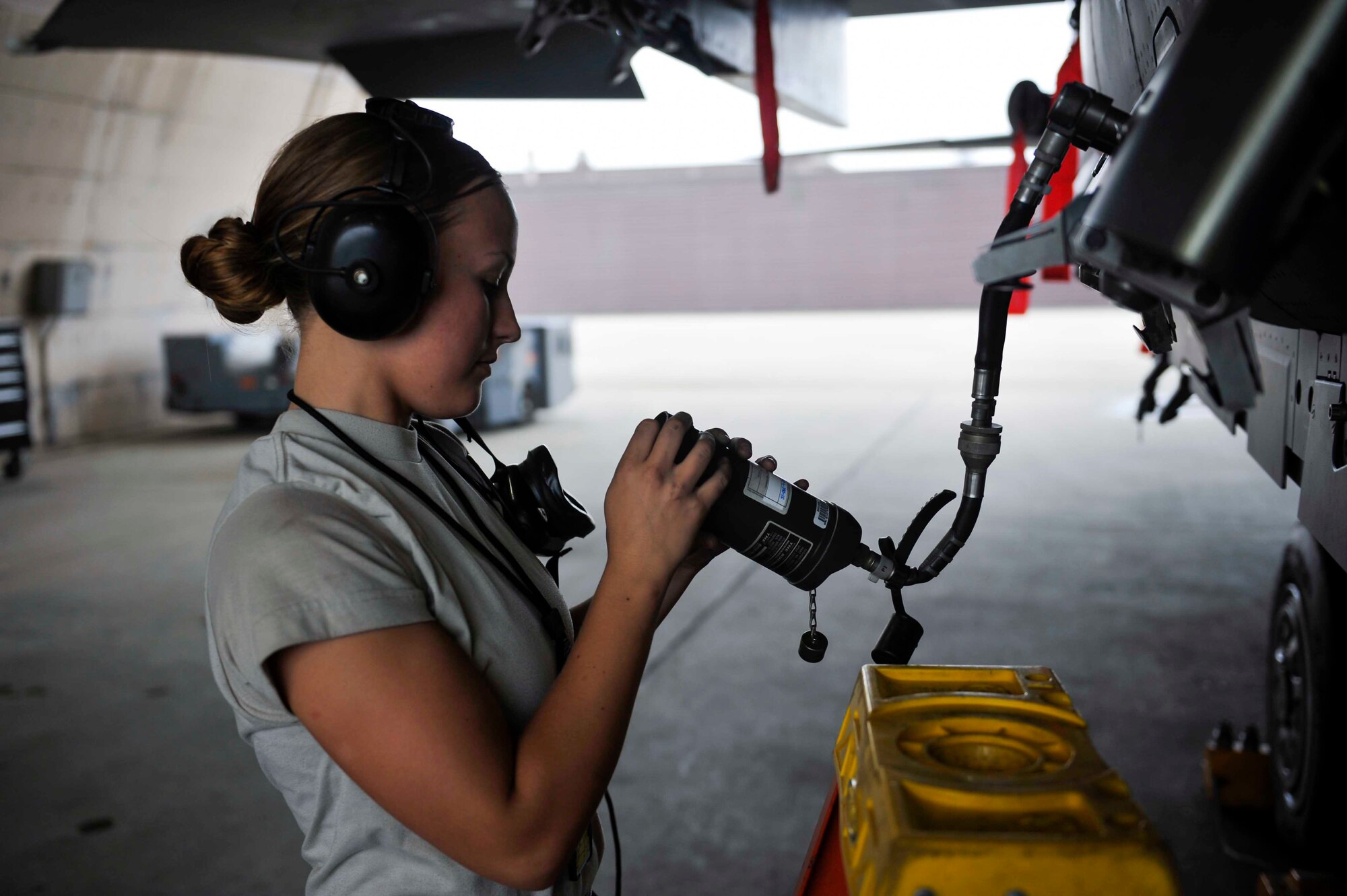 Airman 1st Class Shelby Livingston, 391st Aircraft Maintenance Unit weapons load crew member, Mountain Home Air Force Base, Idaho, looks at a piece of equipment as she and other Airmen perform a conformal fuel tank check on an F-15 Strike Eagle on Osan Air Base, Republic of Korea, Aug. 14, 2014. CFTs are additional fuel tanks fitted closely to the profile of an aircraft. (U.S. Air Force photo/Senior Airman David Owsianka)