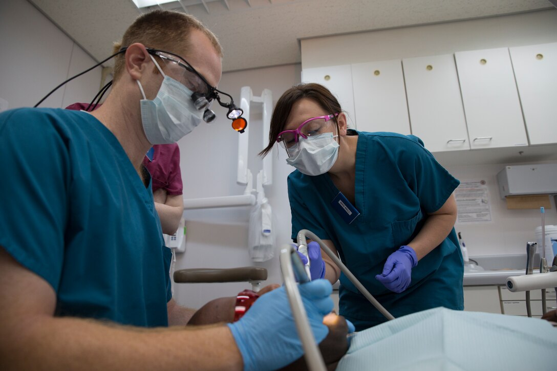 Ashley Bell, a volunteer dental assistant with the American Red Cross, assists Lt. Phillip Jenkins, a dental officer with 11th Dental Company Detachment, while performing a teeth cleaning inside the Robert M. Casey Medical and Dental Clinic aboard Marine Corps Air Station Iwakuni, Japan, August 13, 2014. The American Red Cross, in coordination with 11th Dental Company Detachment, offers Status of Forces Agreement civilians the opportunity to participate in the Dental Assisting Training Program aboard station. The program allows personnel to gain 500 hours toward becoming a certified dental assistant.