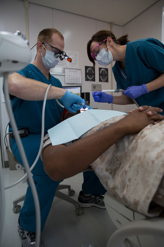 Ashley Bell, a volunteer dental assistant with the American Red Cross, assists Lt. Phillip Jenkins, a dental officer with 11th Dental Company Detachment, while performing a teeth cleaning inside the Robert M. Casey Medical and Dental Clinic aboard Marine Corps Air Station Iwakuni, Japan, August 13, 2014. The American Red Cross, in coordination with 11th Dental Company Detachment, offers Status of Forces Agreement civilians the opportunity to participate in the Dental Assisting Training Program aboard station. The program allows personnel to gain 500 hours toward becoming a certified dental assistant.