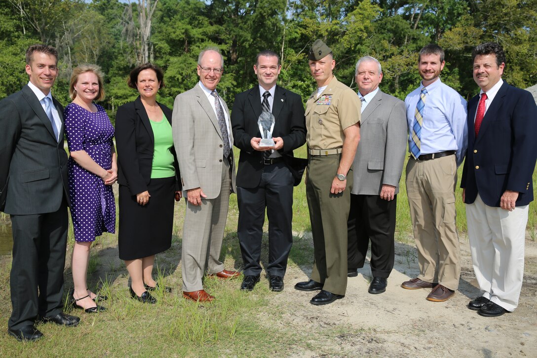 Representatives with the Environmental Affairs Department gather for a photo with Col. Chris Pappas III and Donald R. Schregardus after receiving the 2013 Secretary of the Navy Environmental Restoration Team Award during a ceremony at Marine Corps Air Station Cherry Point, N.C., Aug. 8, 2014. The team received the award for innovative restoration strategies used to prevent and decrease contamination at the air station. Pappas is the commanding officer of Cherry Point and Schregardus is the deputy assistant secretary of the Navy (environment). 