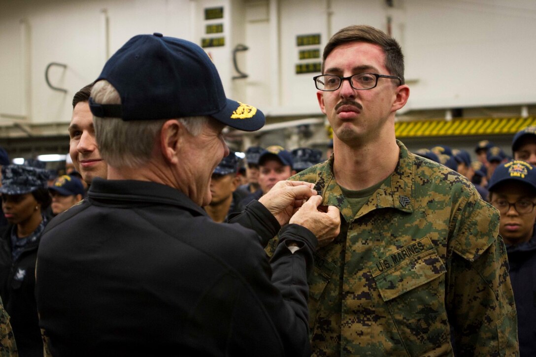 Secretary of the Navy Ray Mabus promotes Sgt. Louis Marrero, a Marine with Marine Operational Test and Evaluation Squadron 22, during a reenlistment and promotion ceremony held aboard the future amphibious assault ship USS America (LHA 6), Aug. 19, 2014. The reenlistment and promotions were held prior to an all hands meeting where Mabus addressed the Marines and Sailors with America and SPMAGTF-South. Mabus also toured the ship, had dinner with Marines and Sailors in the mess deck and attended an ice cream social. Visits like this remind the Marines and Sailors with America and the SPMAGTF of the significance of the work they are doing. SPMAGTF-South is embarked aboard America in support of her maiden transit, “America Visits the Americas.” Through partner-nation activities, theater security events and key leader engagements, the transit aims to demonstrate the flexibility, utility and unparalleled expeditionary capability the Navy-Marine Corps team provides our nation and partners. (U.S. Marine Corps Photo by Cpl. Donald Holbert/ Released)