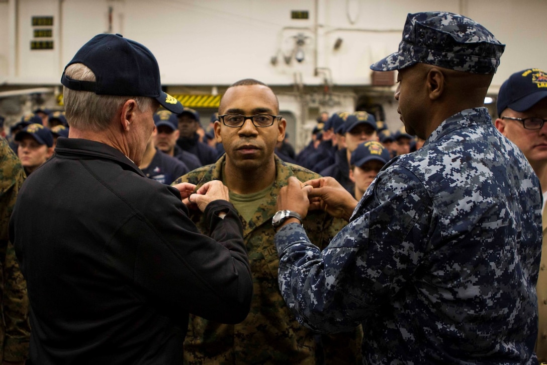 Gunnery Sgt. Cedric Swan (center), a Marine with Expeditionary Strike Group 3, is promoted by Secretary of the Navy Ray Mabus (left) and Rear Adm. Frank L. Ponds, commander of ESG3, during a reenlistment and promotion ceremony aboard the future amphibious assault ship USS America (LHA 6), Aug. 19, 2014. The reenlistment and promotions were held prior to an all hands meeting where Mabus addressed the Marines and Sailors with America and SPMAGTF-South. Mabus also toured the ship, had dinner with Marines and Sailors in the mess deck and attended an ice cream social. Visits like this remind the Marines and Sailors with America and the SPMAGTF of the significance of the work they are doing. SPMAGTF-South is embarked aboard America in support of her maiden transit, “America Visits the Americas.” Through partner-nation activities, theater security events and key leader engagements, the transit aims to demonstrate the flexibility, utility and unparalleled expeditionary capability the Navy-Marine Corps team provides our nation and partners. (U.S. Marine Corps Photo by Cpl. Donald Holbert/ Released)