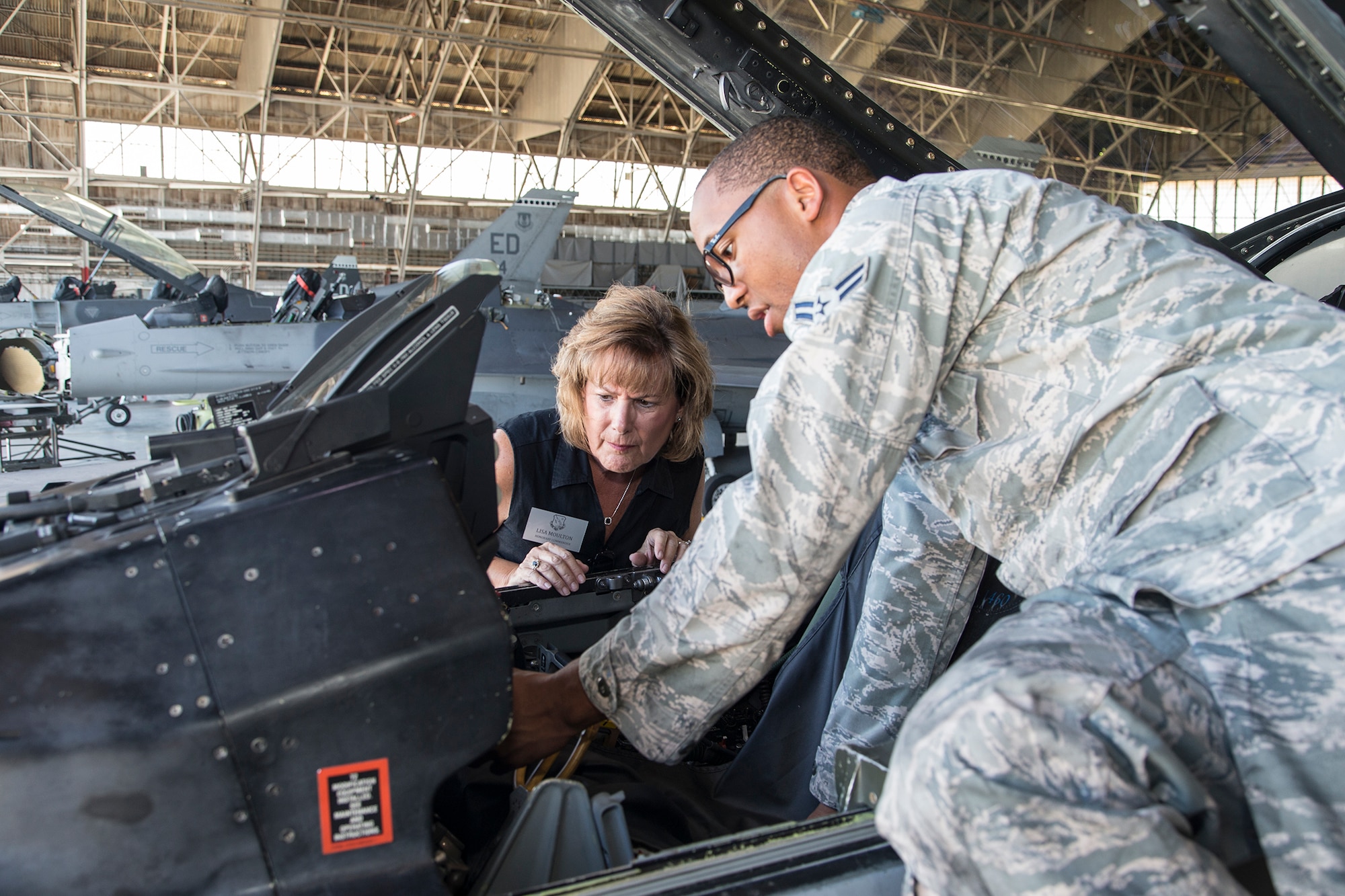 Airman 1st Class Lamonte McCoy (right), from the 412th Aircraft Maintenance Squadron, explains how the flight controls of an F-16 function to Lisa Moulton, honorary commander for the 412th Mission Support Group, during a tour for the 412th Test Wing honorary commanders August 15. (U.S. Air Force photo by Bobbi Zapka)
