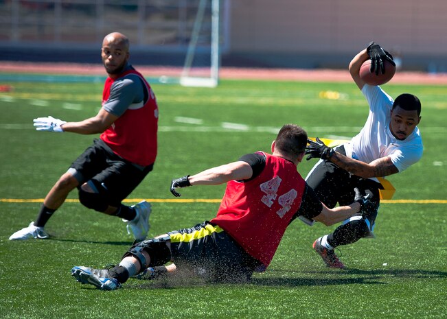 Nellis Airmen compete during flag football tryouts for the base team at Nellis Air Force Base, Nev., Aug. 16, 2014. Airmen participate in team sports as a way of building morale and boosting friendly competition. (U.S. Air Force photo by Airman 1st Class Mikaley Towle)