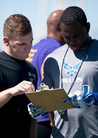 Zac Crawford, (left) 99th Logistics Readiness Squadron, gives his 40-yard dash time to Terrence Kelly, 57th Maintenance Group, during flag-football tryouts at Nellis Air Force Base, Nev., Aug. 16, 2014. The players participated in speed drills to maximize their chances of getting onto the base team. (U.S. Air Force photo by Airman 1st Class Mikaley Towle)