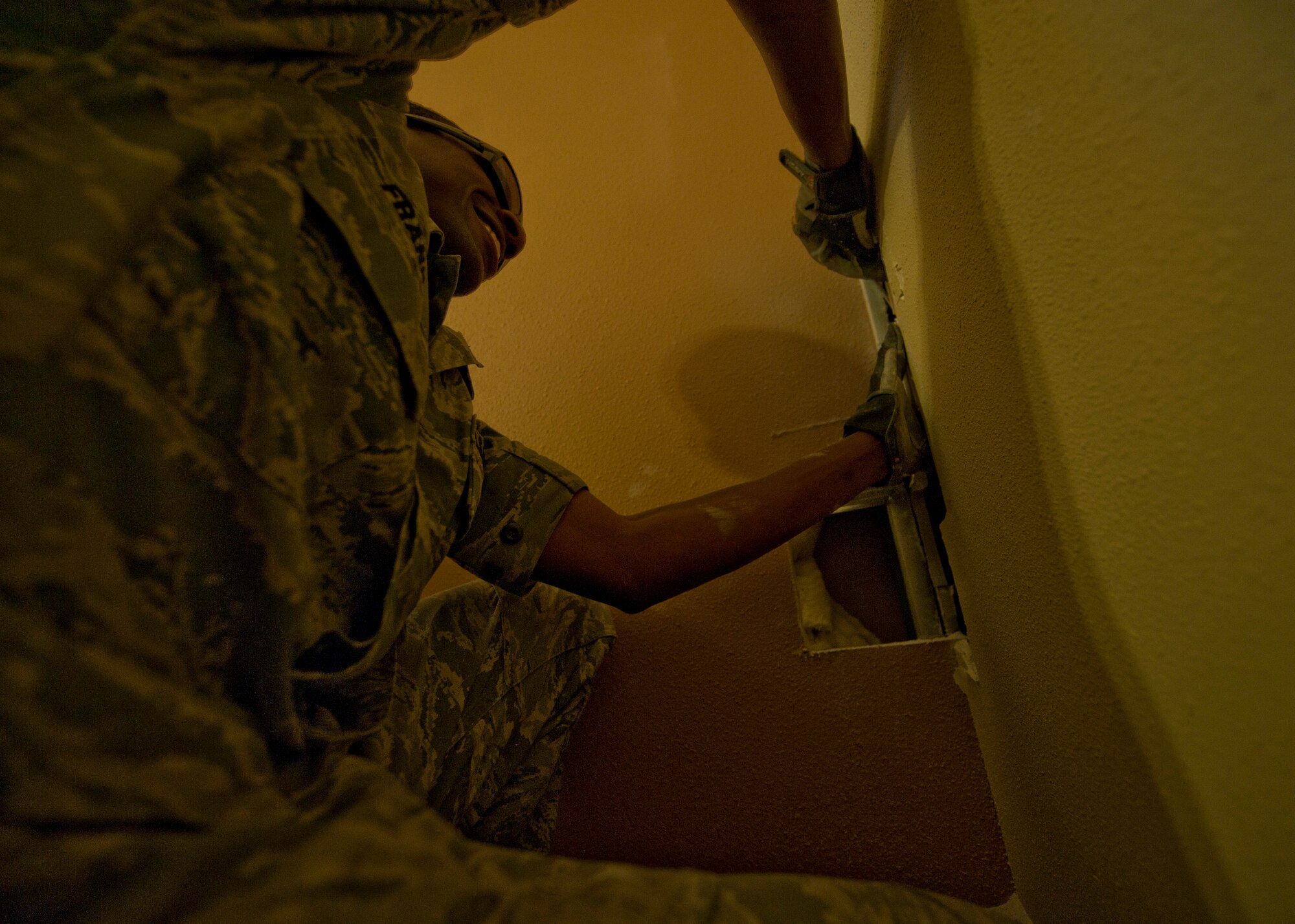 Staff Sgt. Alan Franklin, 99th Civil Engineer Squadron water and fuels systems maintenance craftsman, cuts a hole in the wall to get to a drain pipe at the Nellis Inn on Nellis Air Force Base, Nev., Aug. 19, 2014. Once the hole was cut, Franklin was able to unclog the drain pipe without taking it out of the wall or replacing it. Franklin and other water and fuels systems maintenance technicians are responsible for taking care of all the fire suppression systems and backflow prevention systems, in addition to all of the plumbing systems on base. (U.S. Air Force photo by Staff Sgt. Siuta B. Ika)