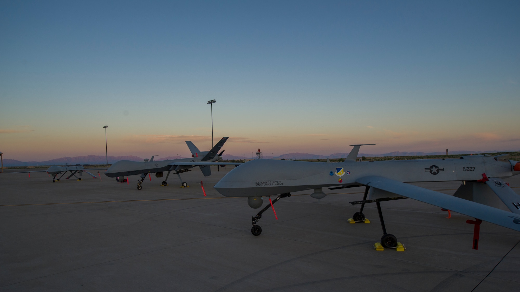 An MQ-1 Predator and MQ-9 Reaper sit on the flight line of Holloman Air Force Base, N.M., Aug. 19, prior to maintenance that will keep them flying and training the next generation of Air Force pilots and sensor operators. The MQ-1 Predator and MQ-9 Reaper both specialize in intelligence, surveillance and reconnaissance. Training for both aircraft is currently centralized at Holloman Air Force Base, N.M.  The MQ-1's primary mission is interdiction and conducting armed reconnaissance against critical, perishable targets. The MQ-9's primary mission is as a persistent hunter-killer against emerging targets to achieve joint force commander objectives.(U.S. Air Force photo by Airman 1st Class Aaron Montoya/Released)