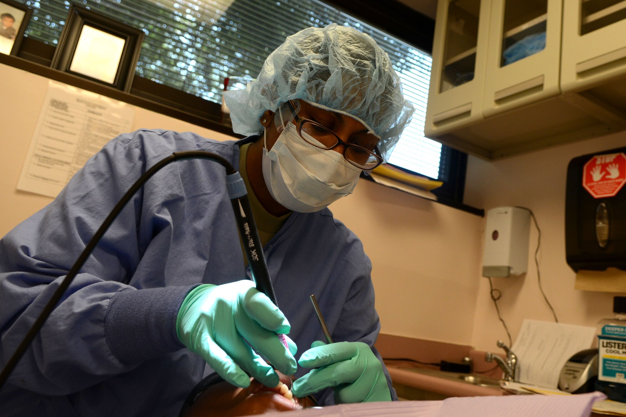 U.S. Air Force Senior Airman Jasmine Mackey, 20th Dental Squadron dental technician, administers an Airman’s annual teeth cleaning at Shaw Air Force Base, S.C., Aug. 20, 2014. The Air Force requires Airmen to have a dental exam once a year to maintain  mission readiness. (U.S. Air Force photo by Senior Airman Ashley L. Gardner/Released)