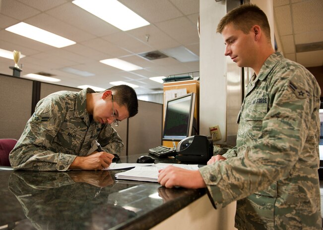 Airman 1st Class Thomas Kelly (left), 99th Comptroller Squadron customer service technician, processes paperwork for Airman 1st Class Weston Maxwell, 757th Aircraft Maintenance Squadron Thunder Aircraft Maintenance Unit avionics technician, at Nellis Air Force Base, Nev., Aug. 18, 2014. The Nellis finance office, which has the largest customer flow of all Air Combat Command bases, fields more than 150-200 customer inquiries every day. (U.S. Air Force photo by Airman 1st Class Thomas Spangler)