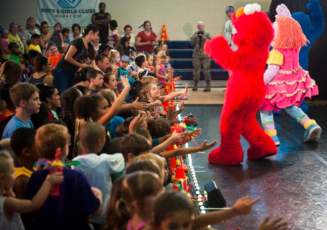 Elmo and other Sesame Street members interact with the crowd during a Sesame Street/USO Experience for Military Families show at the Youth Center, Nellis AFB, Nev., Aug. 15, 2014. Since its debut six years ago, the tour has delivered special family moments to more than 412,000 military children and their parents through approximately 735 shows at 144 military bases in 33 states and 11 countries. (U.S. Air Force photo by Staff Sgt. Siuta B. Ika)