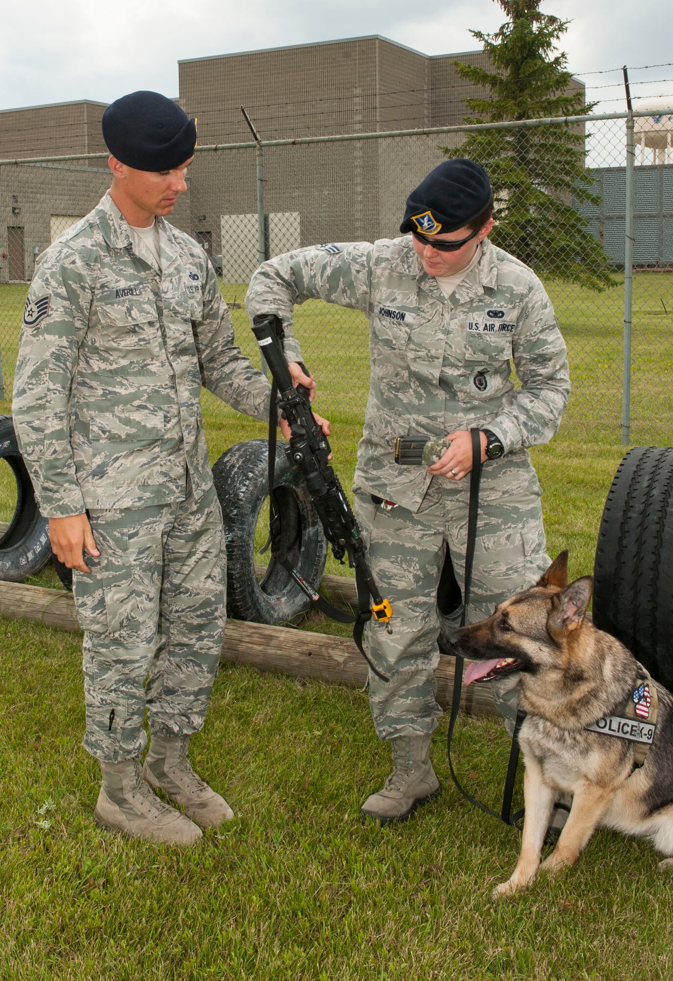 Staff Sgt. Christopher Averill, 5th Security Forces Squadron military working dog trainer, hands a practice weapon to Senior Airman Heather Johnson, 5th SFS MWD handler, during weapons training with her MWD Cyndy on Minot Air Force Base, N.D., July 29, 2014. Averill adheres to a master training plan that outlines the requirements for new handlers. He also works side by side with the handlers to demonstrate proper techniques and methods for working with their MWD. (U.S. Air Force photo/Senior Airman Stephanie Morris)