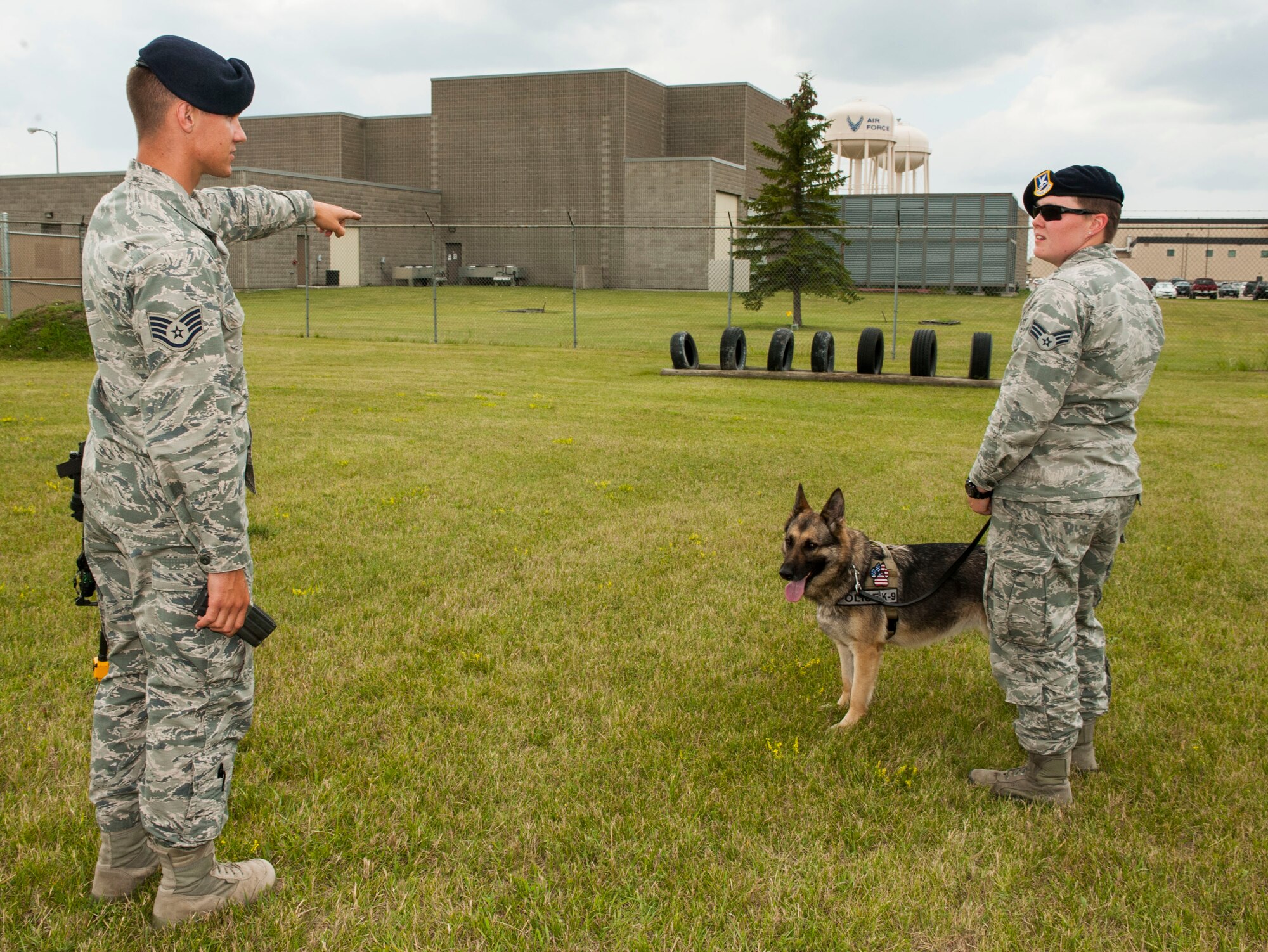 Staff Sgt. Christopher Averill, 5th Security Forces Squadron military working dog trainer, instructs Senior Airman Heather Johnson, 5th SFS MWD handler, on where to begin weapons training with her MWD Cyndy on Minot Air Force Base, N.D., July 29, 2014. Averill has worked in the K-9 career field since December of 2011. Upon becoming the trainer at the kennels, Averill took responsibility for the certification and training of all handlers stationed here. (U.S. Air Force photo/Senior Airman Stephanie Morris)