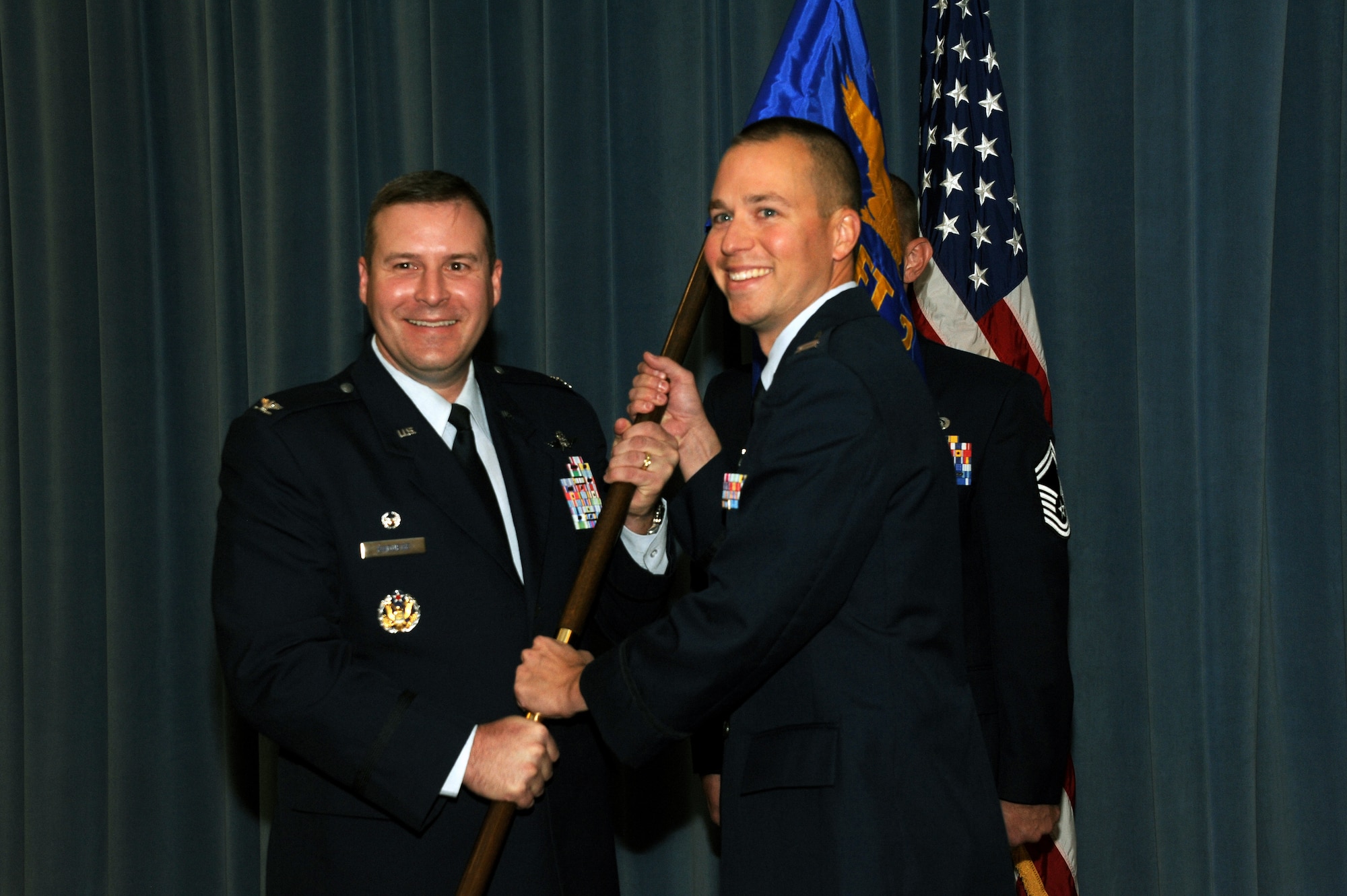 Col. Chad Raduege, left, 690th Cyberspace Operations Group commander, passes the colors to incoming commander Capt. Timothy Labinski, 26th Network Operations Squadron operation flight commander at Maxwell Air Force Base, Ala., Aug. 15, 2014. Labinski is assuming command of the 690th Network Support Squadron from Lt. Col Eric Trias. (U.S Air Force photo by Airman 1st Class Alexa Culbert)