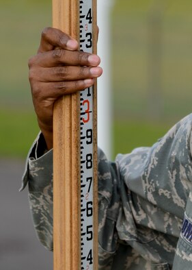 U.S. Air Force Staff Sgt. Erik Holloman, 100th Civil Engineer Squadron engineering assistant from Washington, D.C., holds a measuring tool Aug. 18, 2014, on RAF Mildenhall, England. The tool measures the amount of soil on top of a munitions igloo. (U.S. Air Force photo/Airman 1st Class Victoria H. Taylor/Released)