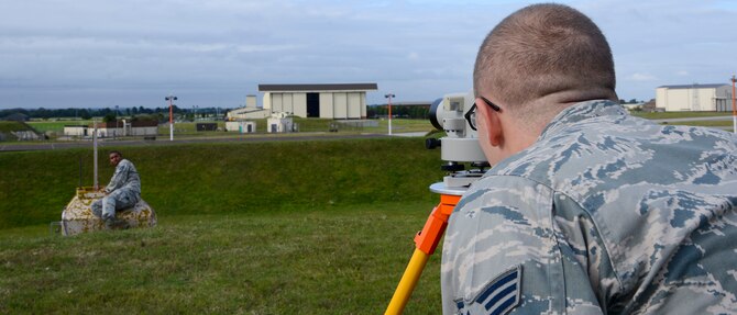 U.S. Air Force Senior Airman Logan Fountaine, right, 100th Civil Engineer Squadron engineering assistant from Ontario, N.Y., and Staff Sgt. Erik Holloman, 100th CES engineering assistant from Washington D.C., use measuring tools Aug. 18, 2014, on RAF Mildenhall, England. The tools are used for a yearly inspection which measures the amount of soil on top of munitions igloos on base. (U.S. Air Force photo/Airman 1st Class Victoria H. Taylor/Released)
