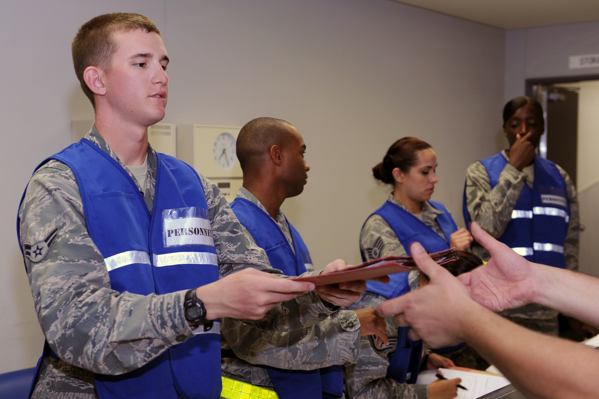 U.S. Air Force Airman 1st Class Shane Roberts, 18th Force Support Squadron employments technician, hands a mobility folder back to its owner at a personnel deployment function line on Kadena Air Base, Japan, Aug. 19, 2014. PDF lines prepare Airmen for deployment by ensuring they have the paperwork and equipment that would be necessary during real-world contingencies. (U.S. Air Force photo by Airman 1st Class Zade C. Vadnais/Released)